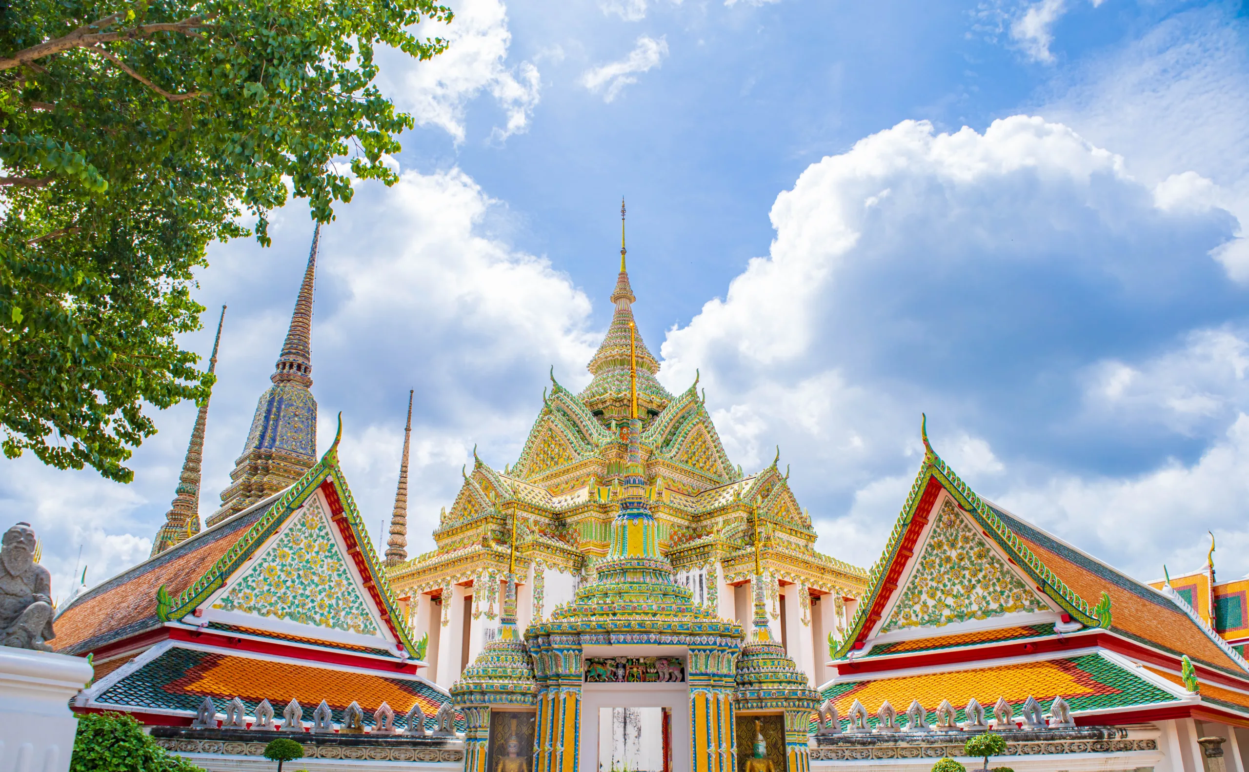 Kolorowe i bogato zdobione pagody oraz świątynie w Wat Pho, Bangkok, Tajlandia, na tle błękitnego nieba z chmurami - światynie w Bangkoku