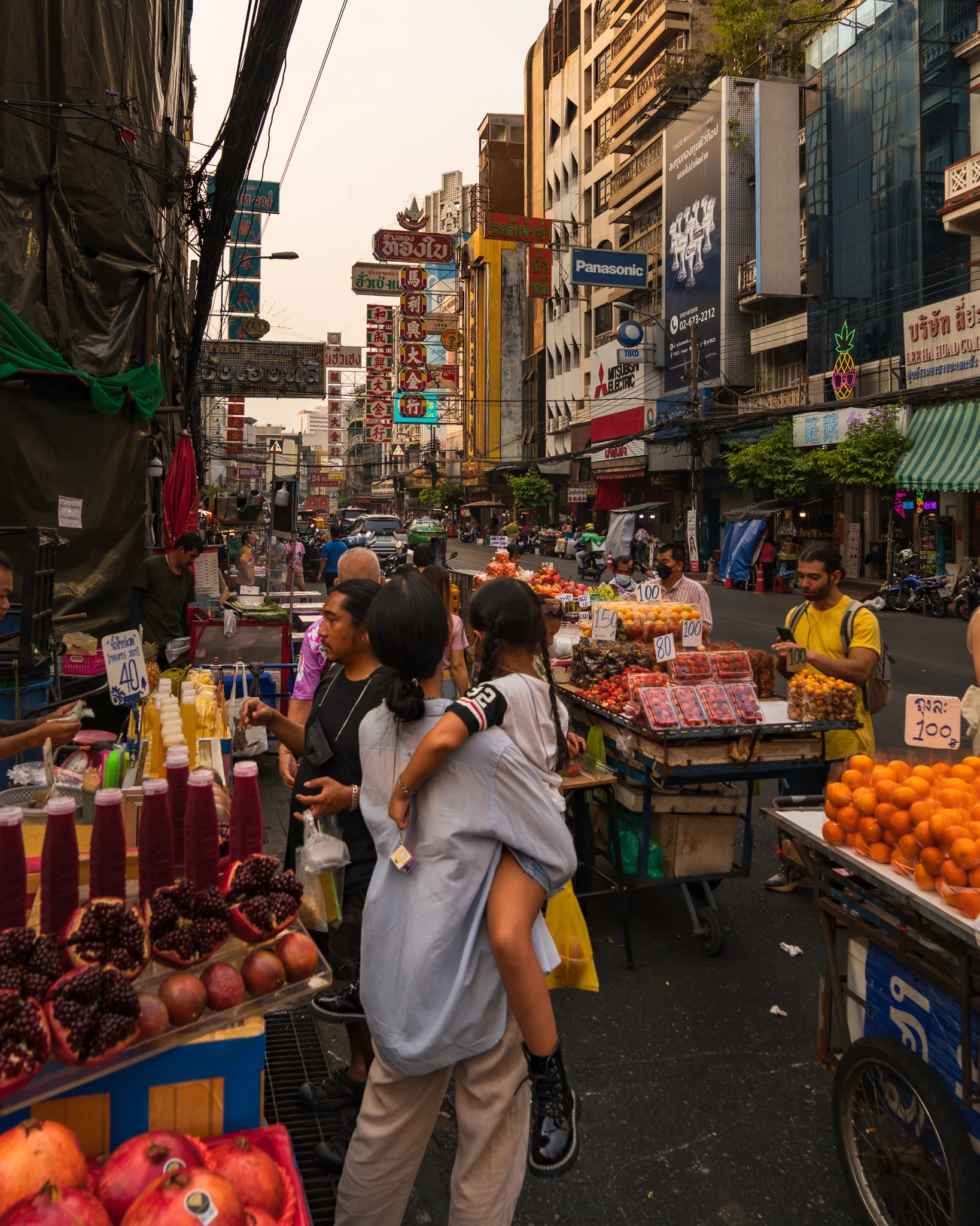 Targ uliczny w dzielnicy Chinatown w Bangkoku z owocami, sokami i ludźmi robiącymi zakupy