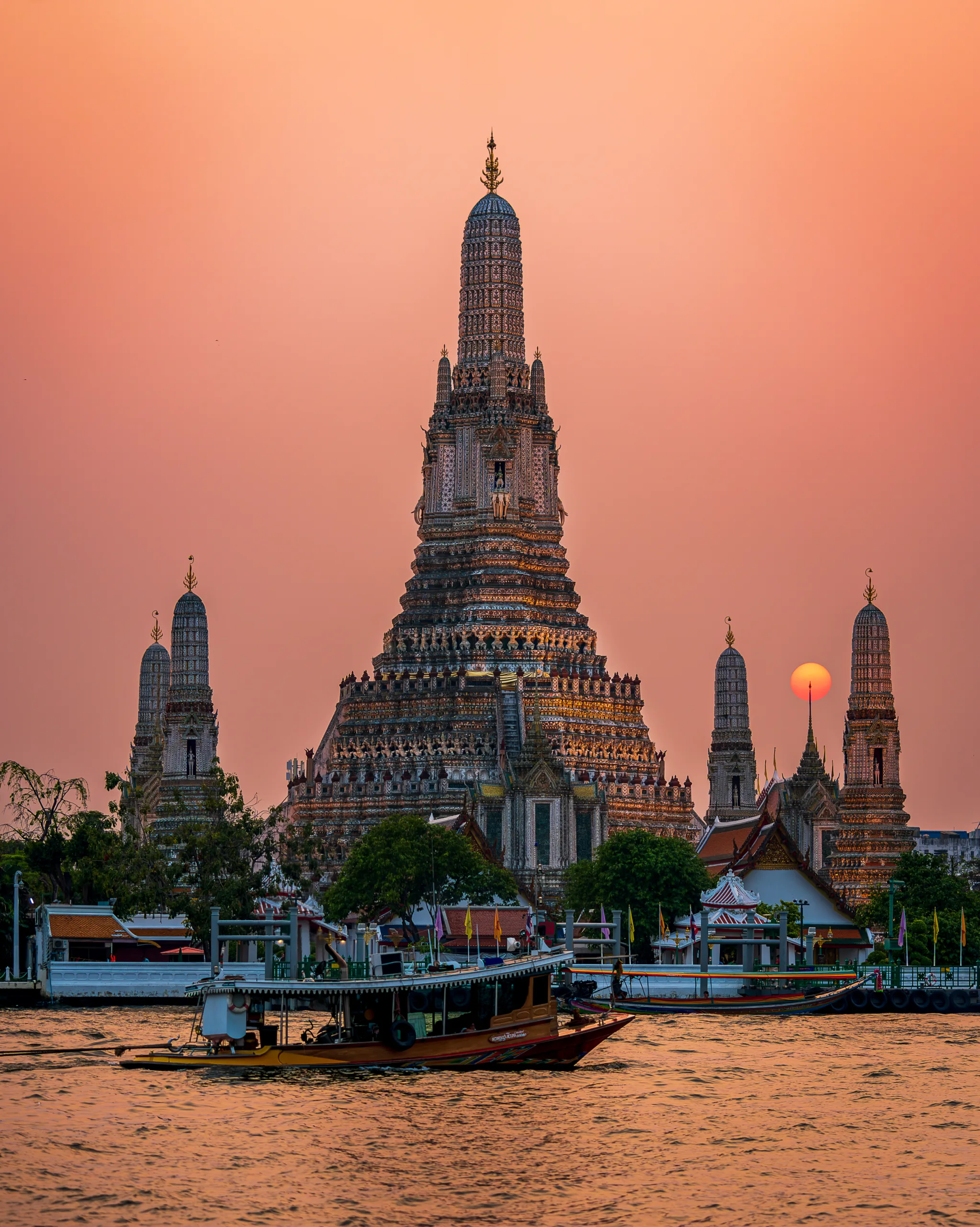 Świątynia Wat Arun w Bangkoku o zachodzie słońca z łodzią na rzece Chao Phraya