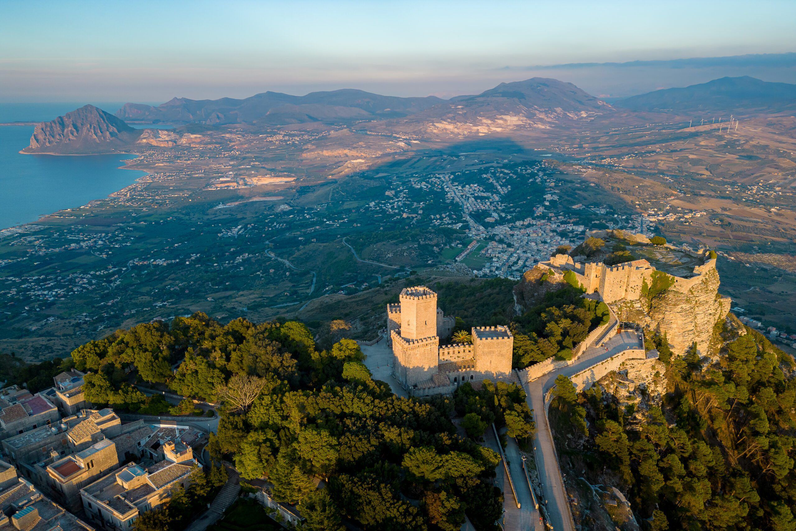 Zamek Wenus w Erice na Sycylii o zachodzie słońca, z panoramicznym widokiem na wybrzeże i górzysty krajobraz