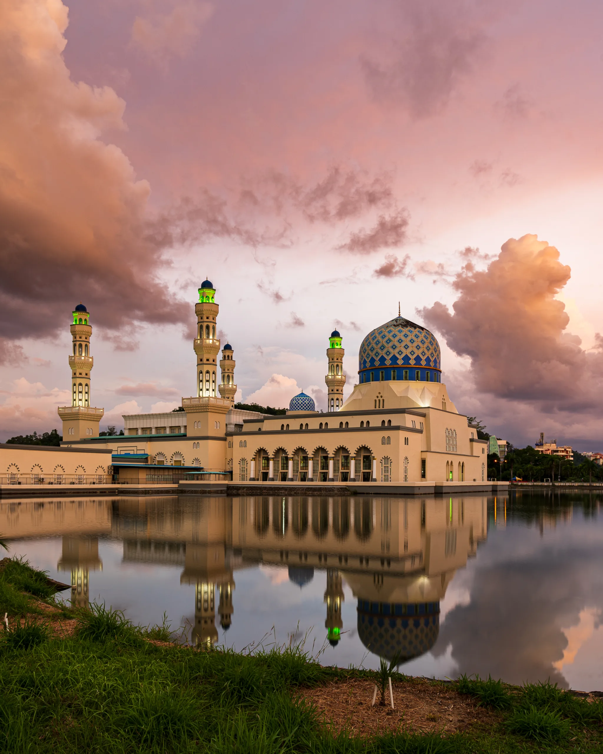 Meczet Likas Bay w Kota Kinabalu o zachodzie słońca, odbijający się w spokojnej tafli wody.