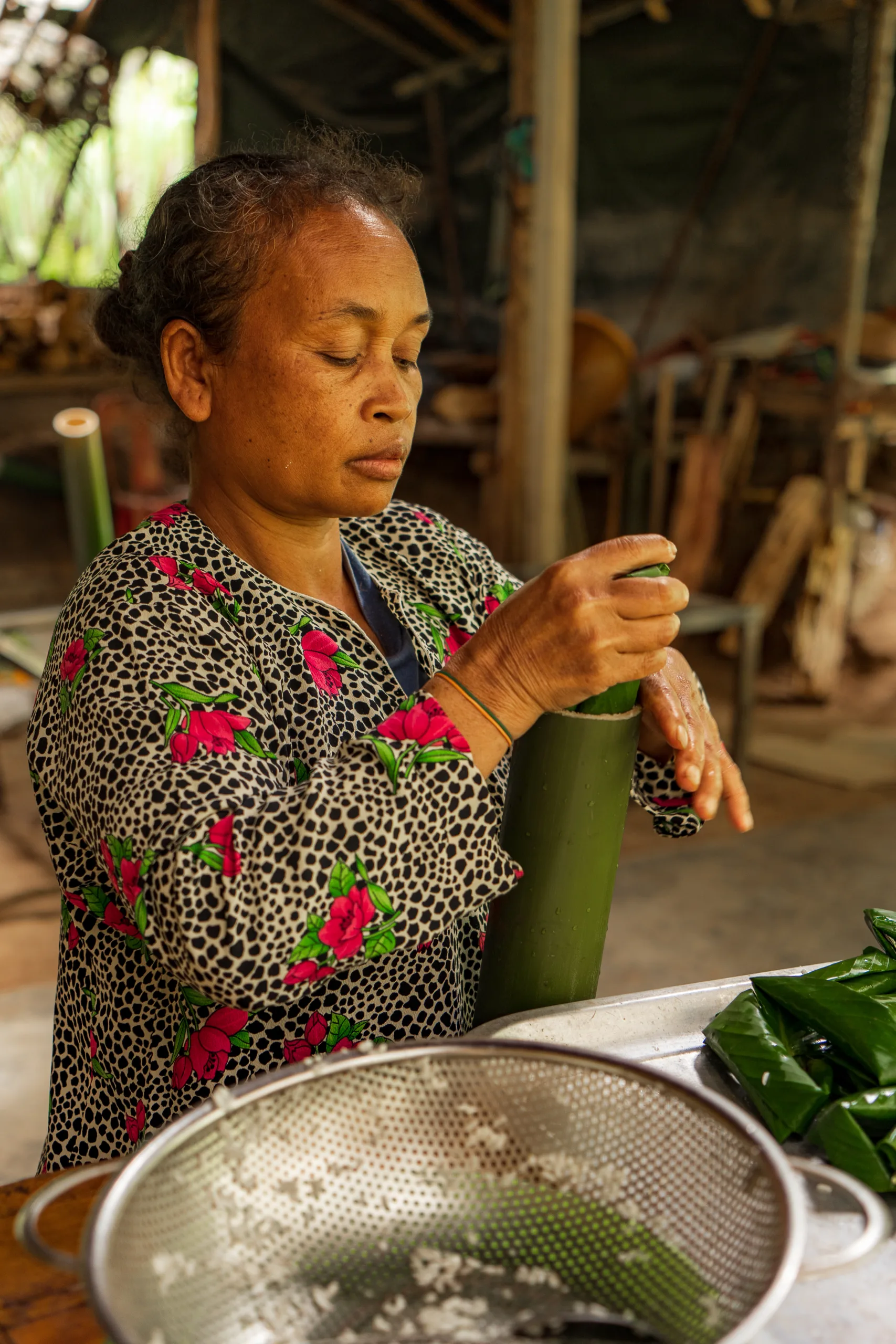 Kobieta w tradycyjnym stroju przygotowuje potrawę w bambusowej rurze w malezyjskiej wiosce.
