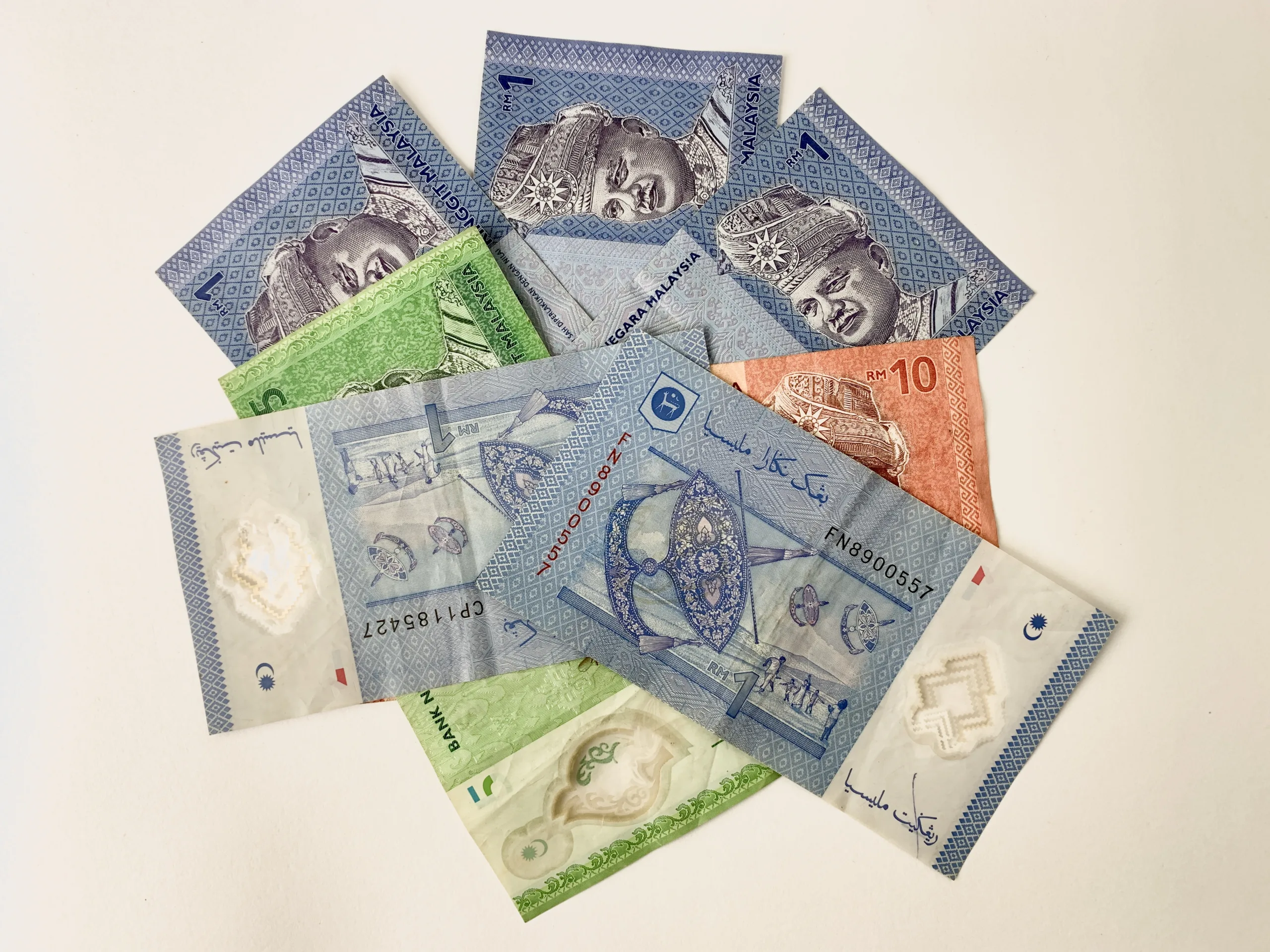 Malezyjskie banknoty w nominałach od 1 do 10 ringgitów, ułożone na białym tle.