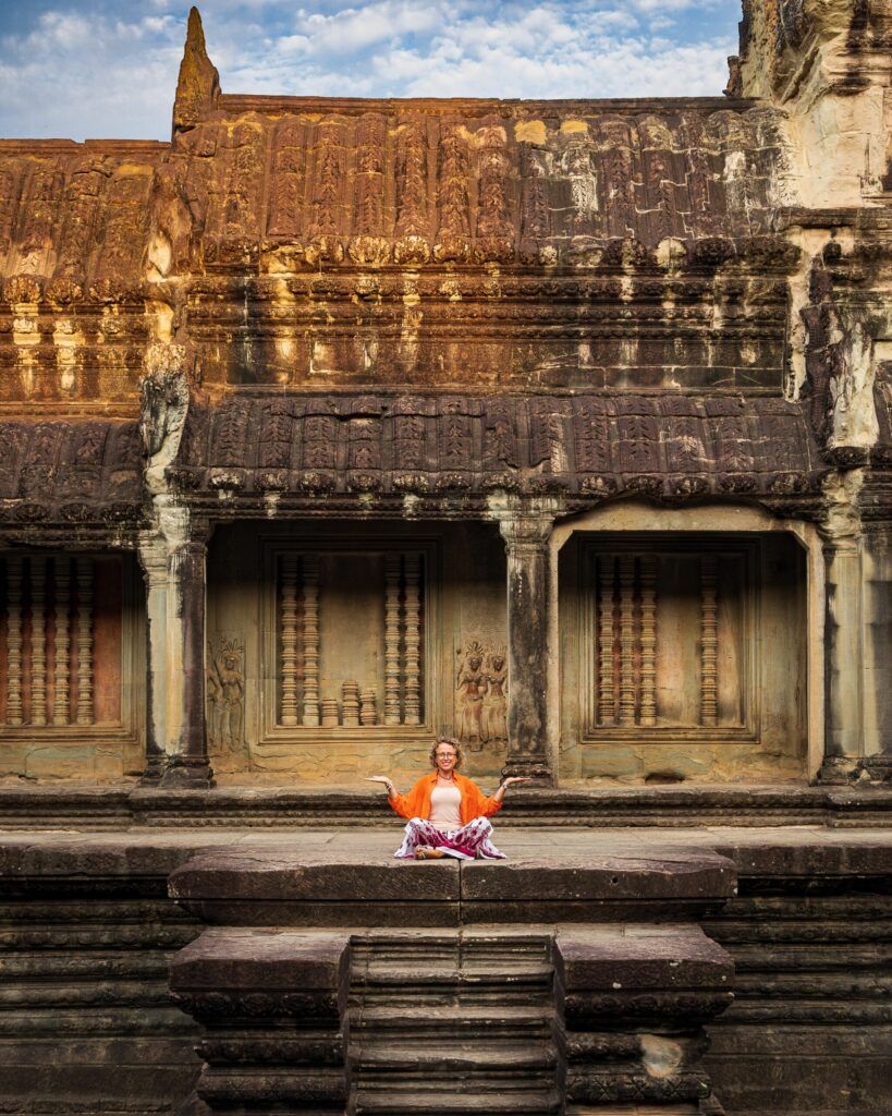 Turystka medytująca na schodach świątyni Angkor Wat w Kambodży, otoczona starożytną kamienną architekturą.