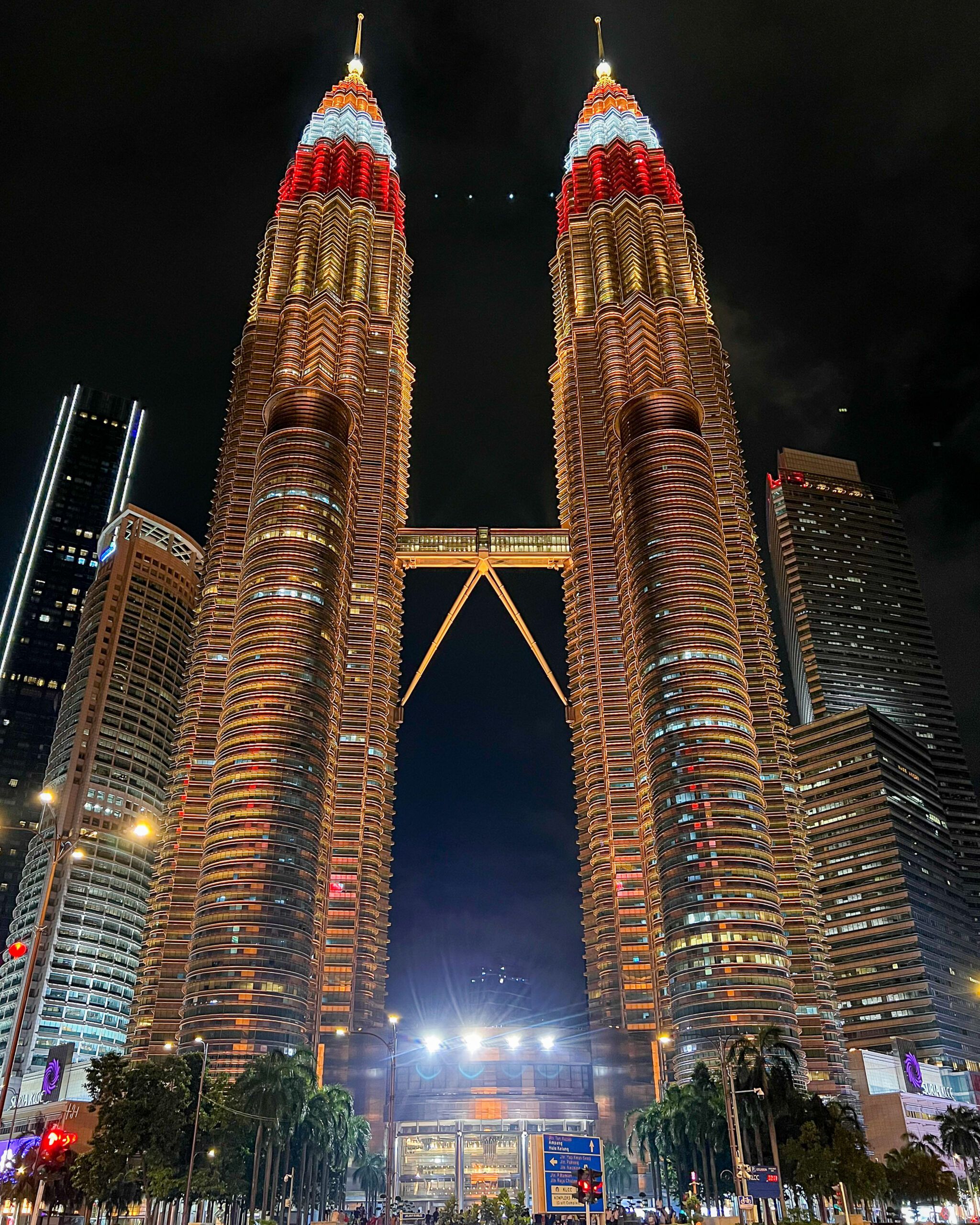 Nocny widok na Petronas Towers w Kuala Lumpur z czerwono-białym oświetleniem i iluminacją w dolnej części budynku.