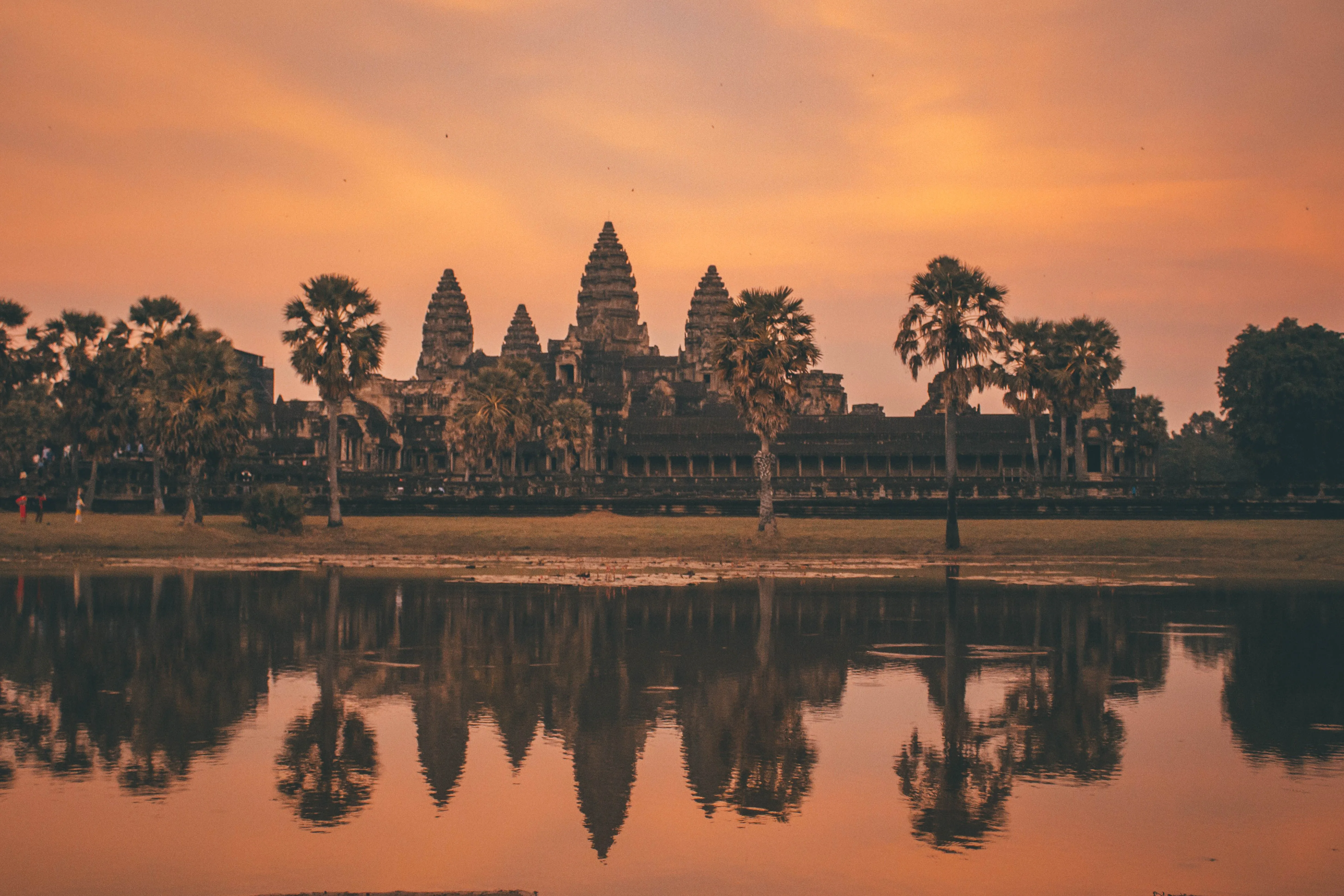 Angkor Wat o wschodzie słońca z odbiciem świątyni i palm w wodzie w Siem Reap w Kambodży.
