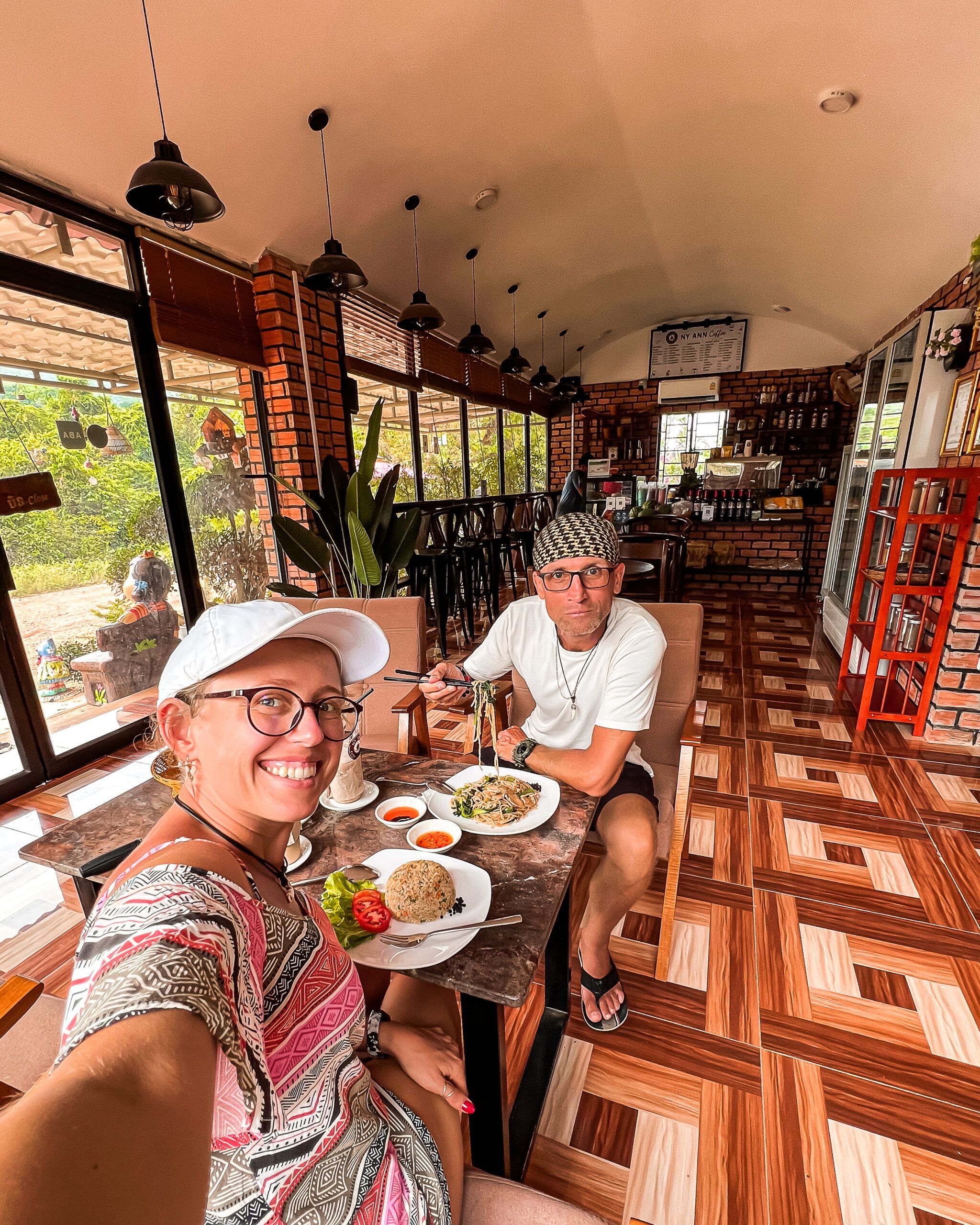 Para turystów w azjatyckiej restauracji, siedzących przy stole z tradycyjnymi daniami – smażonym ryżem i makaronem z warzywami.