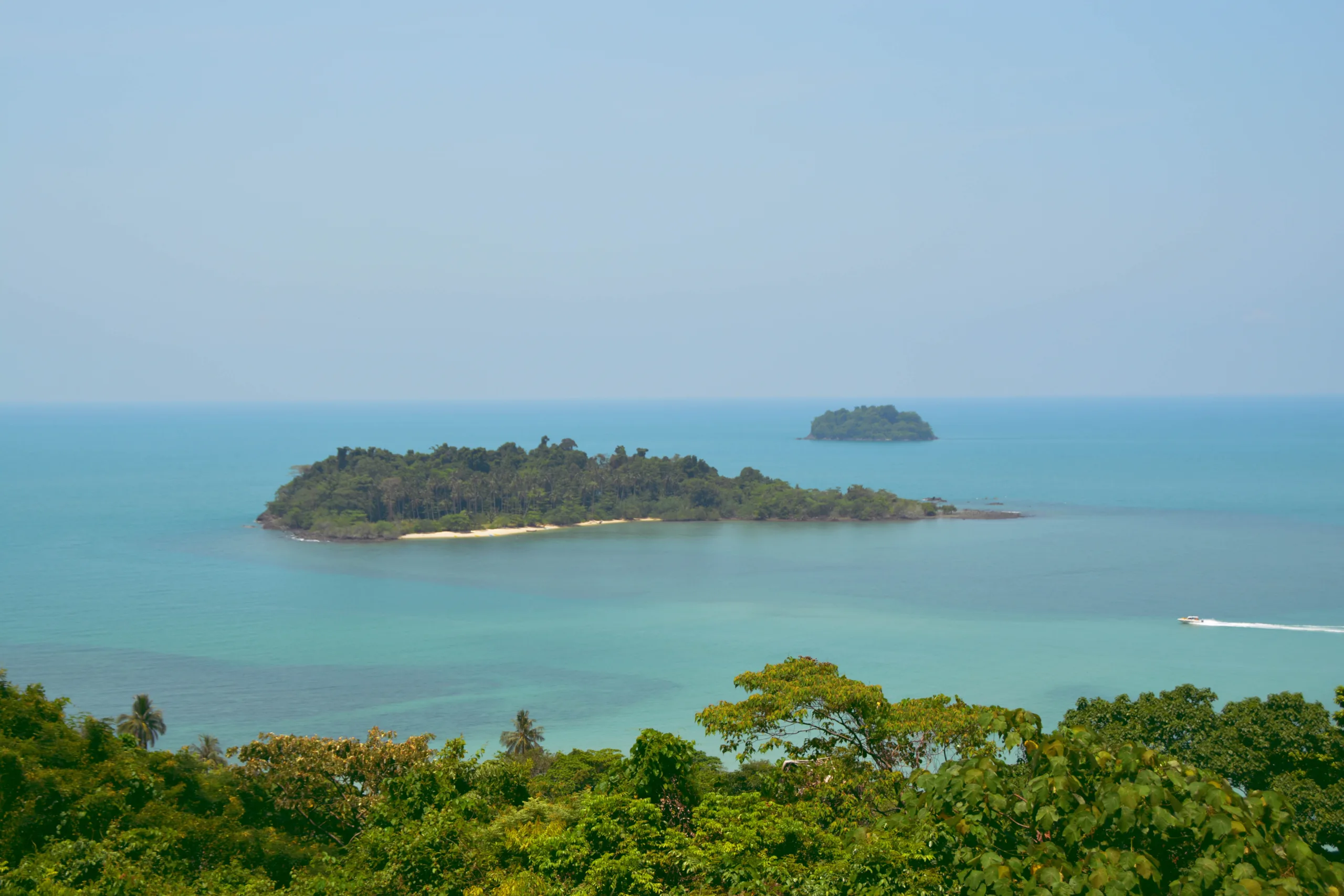 Tropikalna wyspa otoczona turkusowym morzem z motorówką płynącą w oddali – spokojny krajobraz Tajlandii - Koh Chang - Koh Man Nai