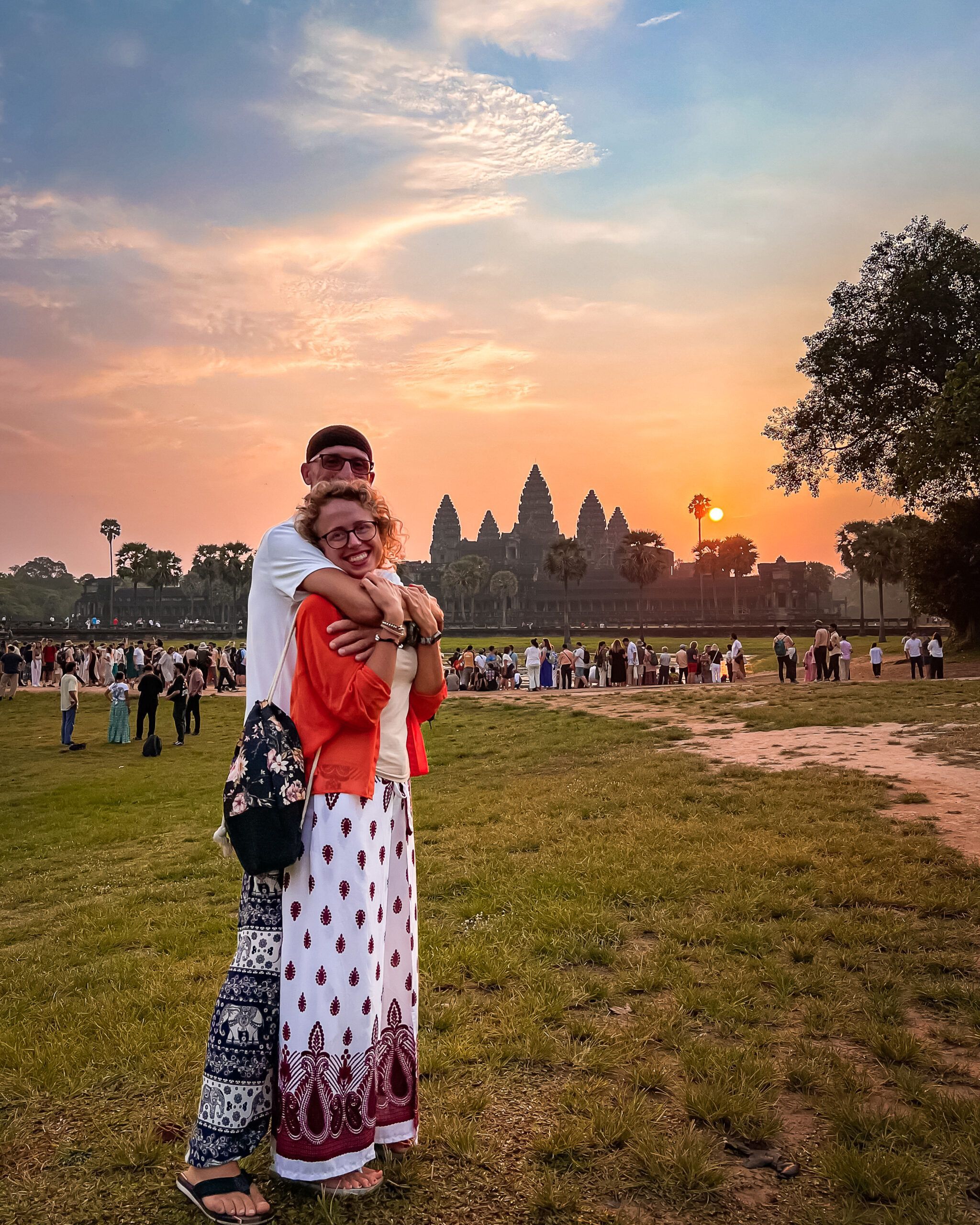 Para podróżników obejmująca się na tle świątyni Angkor Wat o wschodzie słońca w Kambodży.