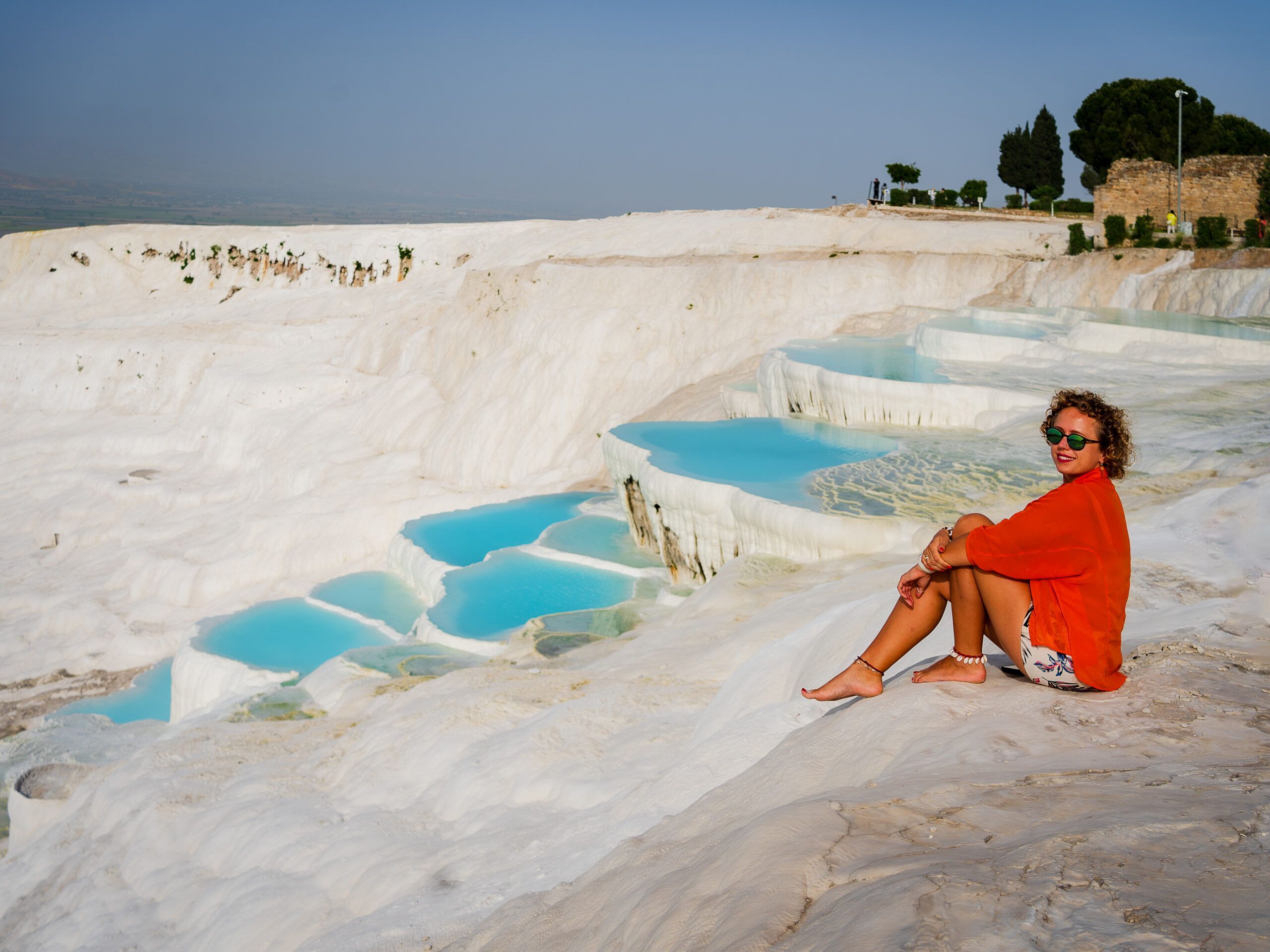 Pamukkale, czyli „Bawełniany Zamek”, to zespół śnieżnobiałych, wapiennych tarasów, powstałych przez osadzanie się minerałów z gorących źródeł.
Woda płynie tu kaskadami, tworząc naturalne baseny – efekt? Widok jak z innej planety.
