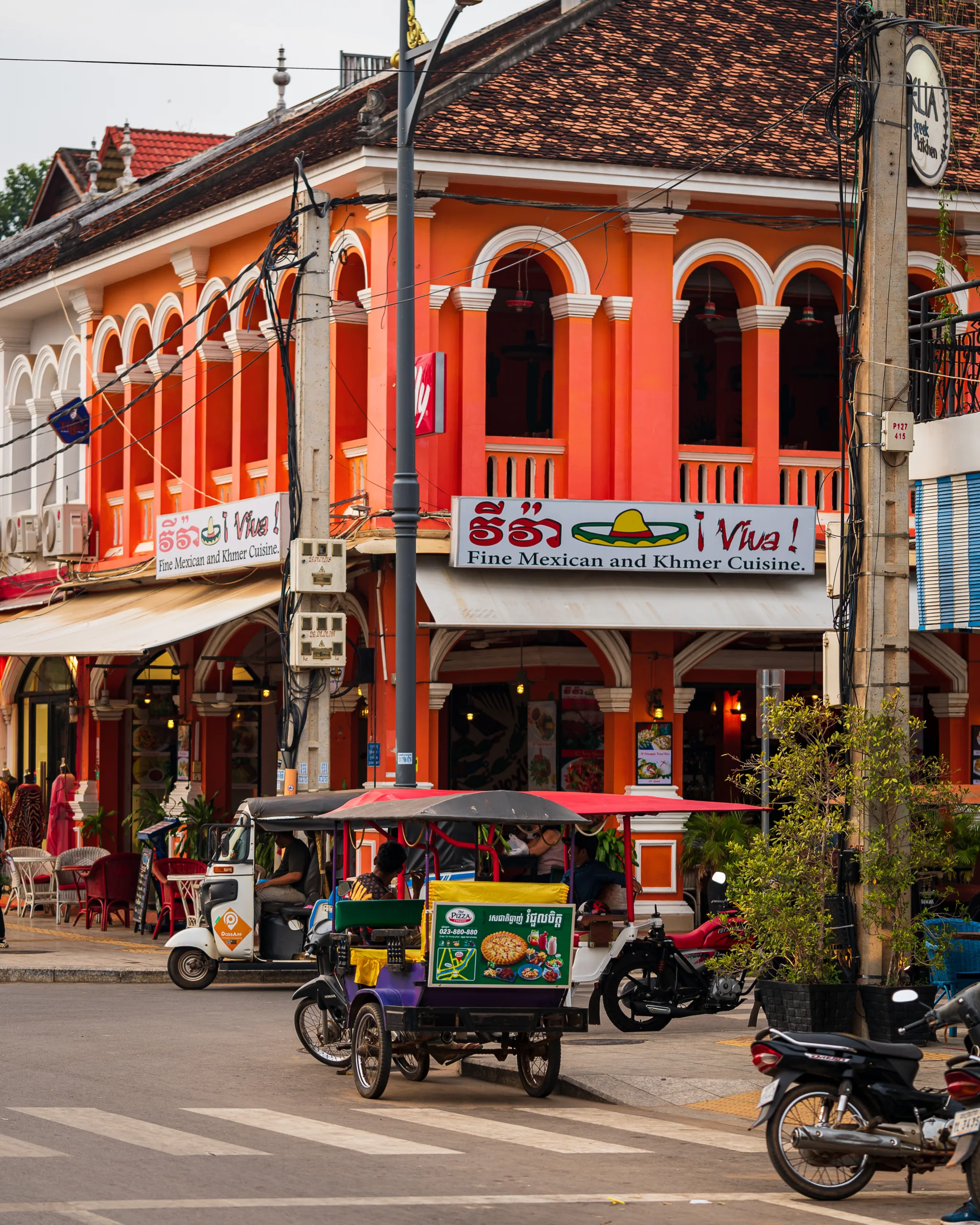 Kolorowa kamienica w Siem Reap z restauracją serwującą kuchnię meksykańską i khmerską, a przed nią tuk-tuki na ulicy.