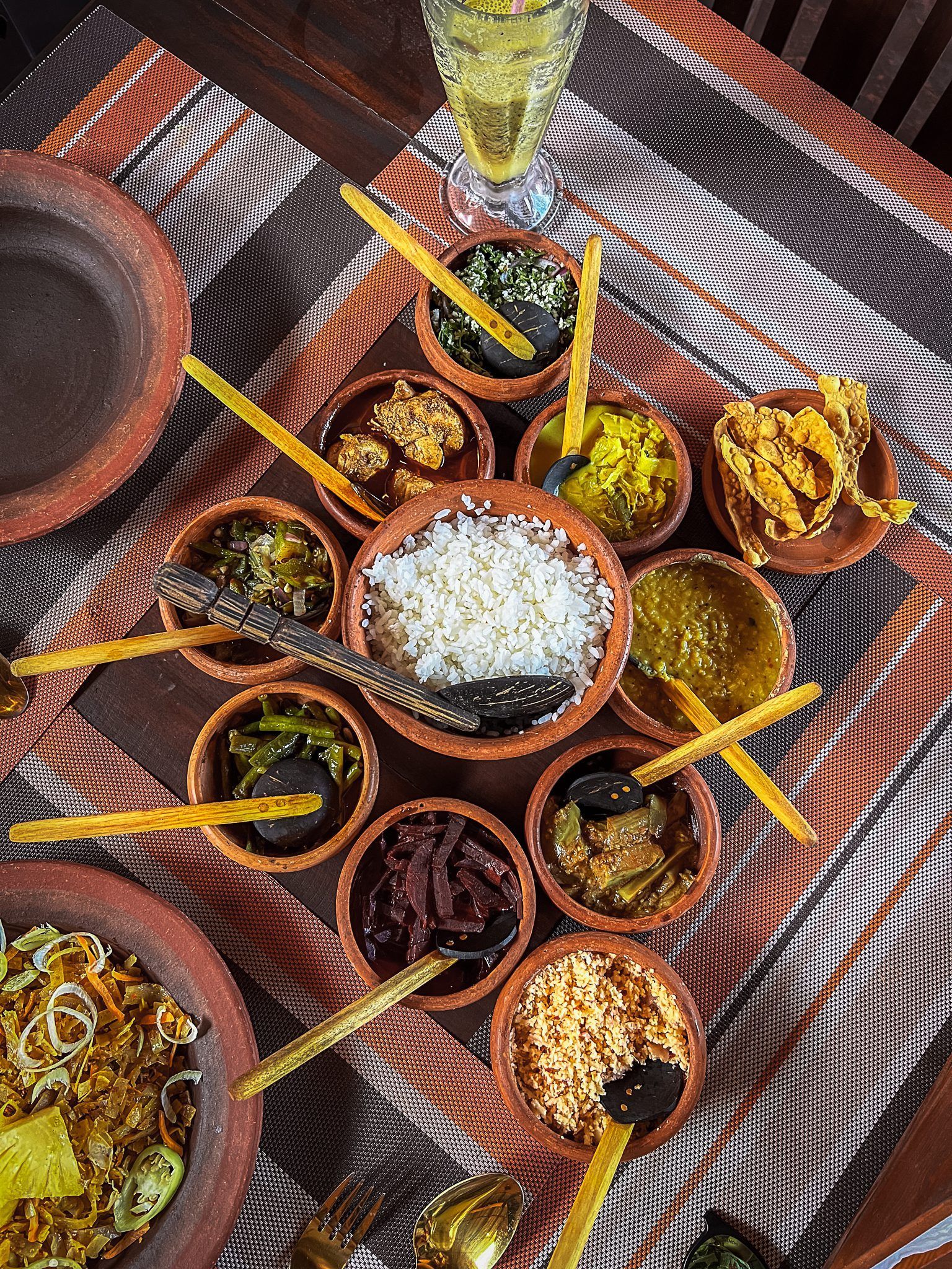 Tradycyjny lankijski posiłek rice and curry podany w glinianych miseczkach – ryż, curry warzywne, sambol i dodatki