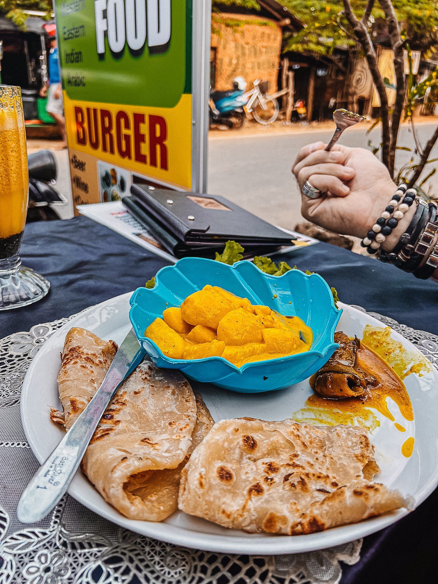 Tradycyjne lankijskie śniadanie z roti, curry i świeżym mango podane na ulicznym stoliku.