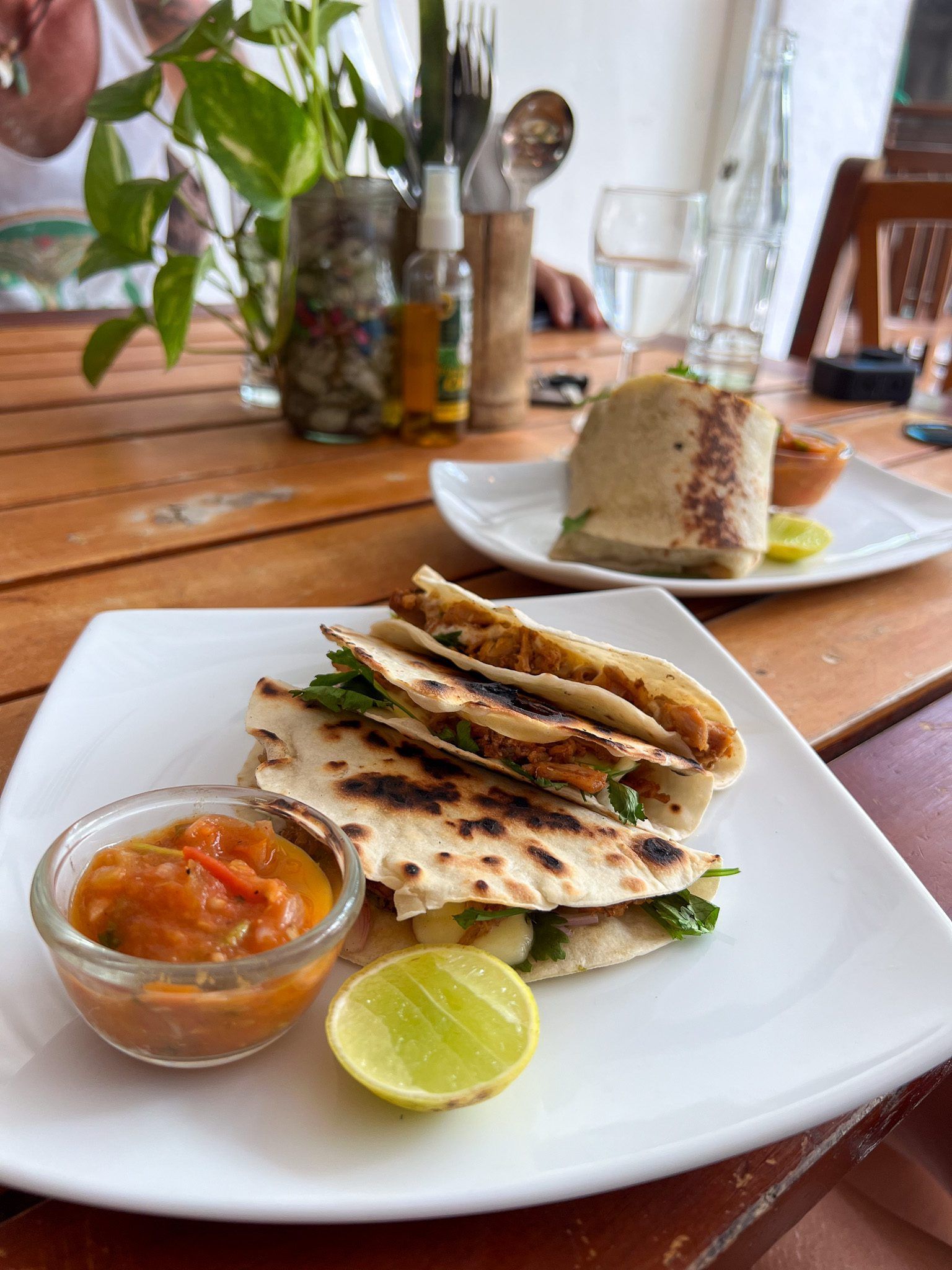 Quesadilla z grillowaną tortillą, warzywami i mięsem, podana z sosem pomidorowym i kawałkiem limonki.