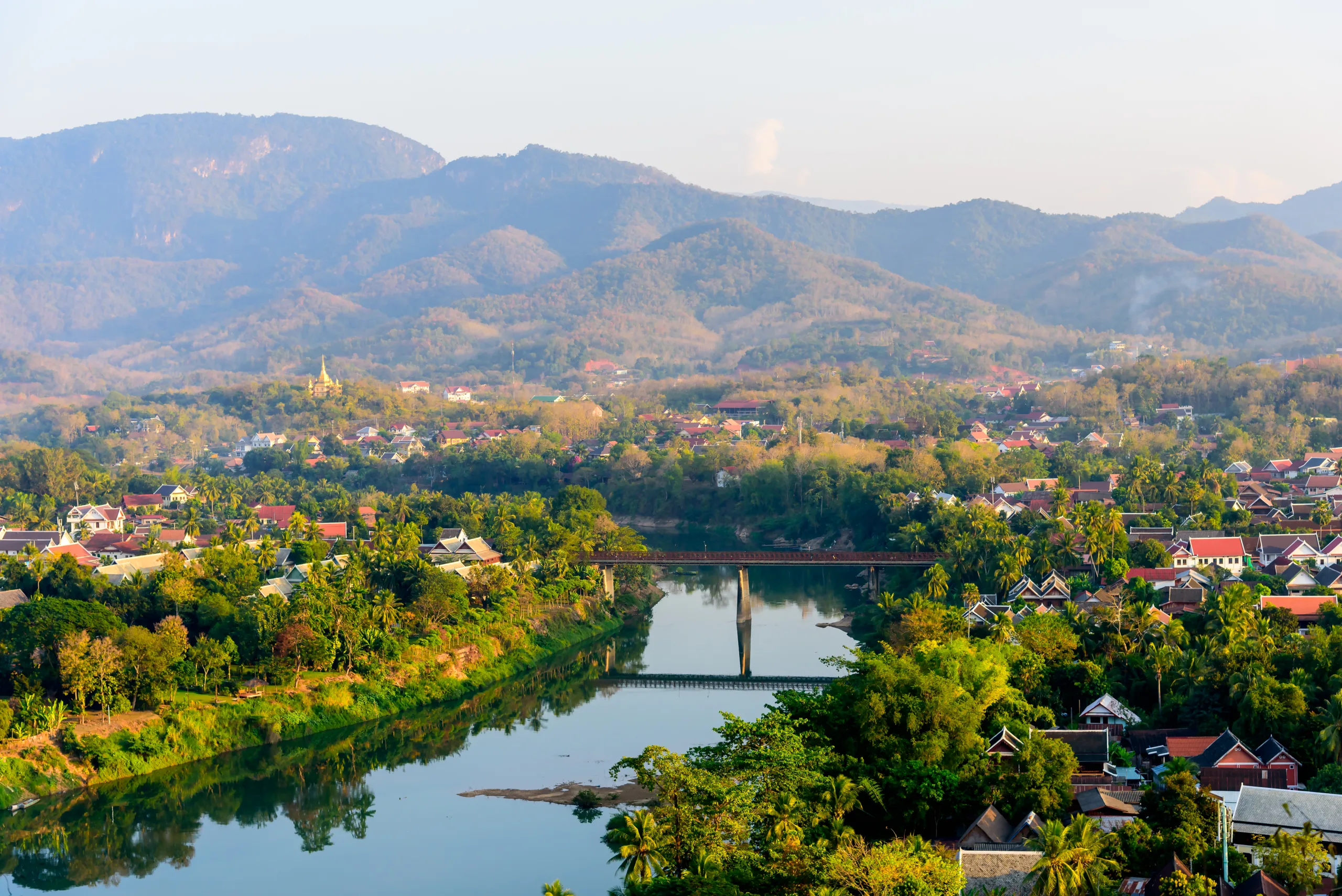 Panorama miasta Luang Prabang z widokiem na rzekę Khan, most i otaczające wzgórza o poranku.