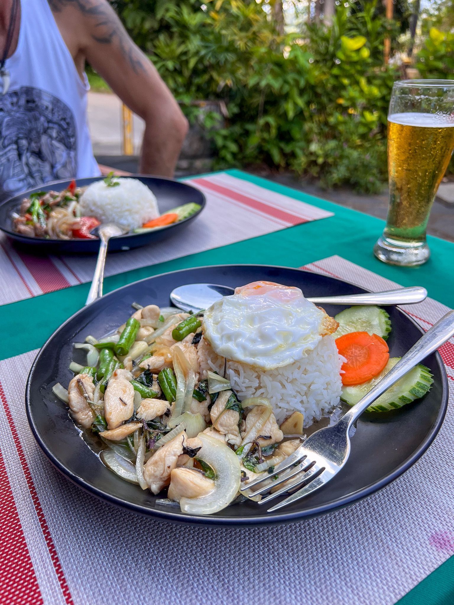 Talerz tajskiego dania z kurczakiem, warzywami, ryżem i jajkiem sadzonym podany w restauracji na świeżym powietrzu.