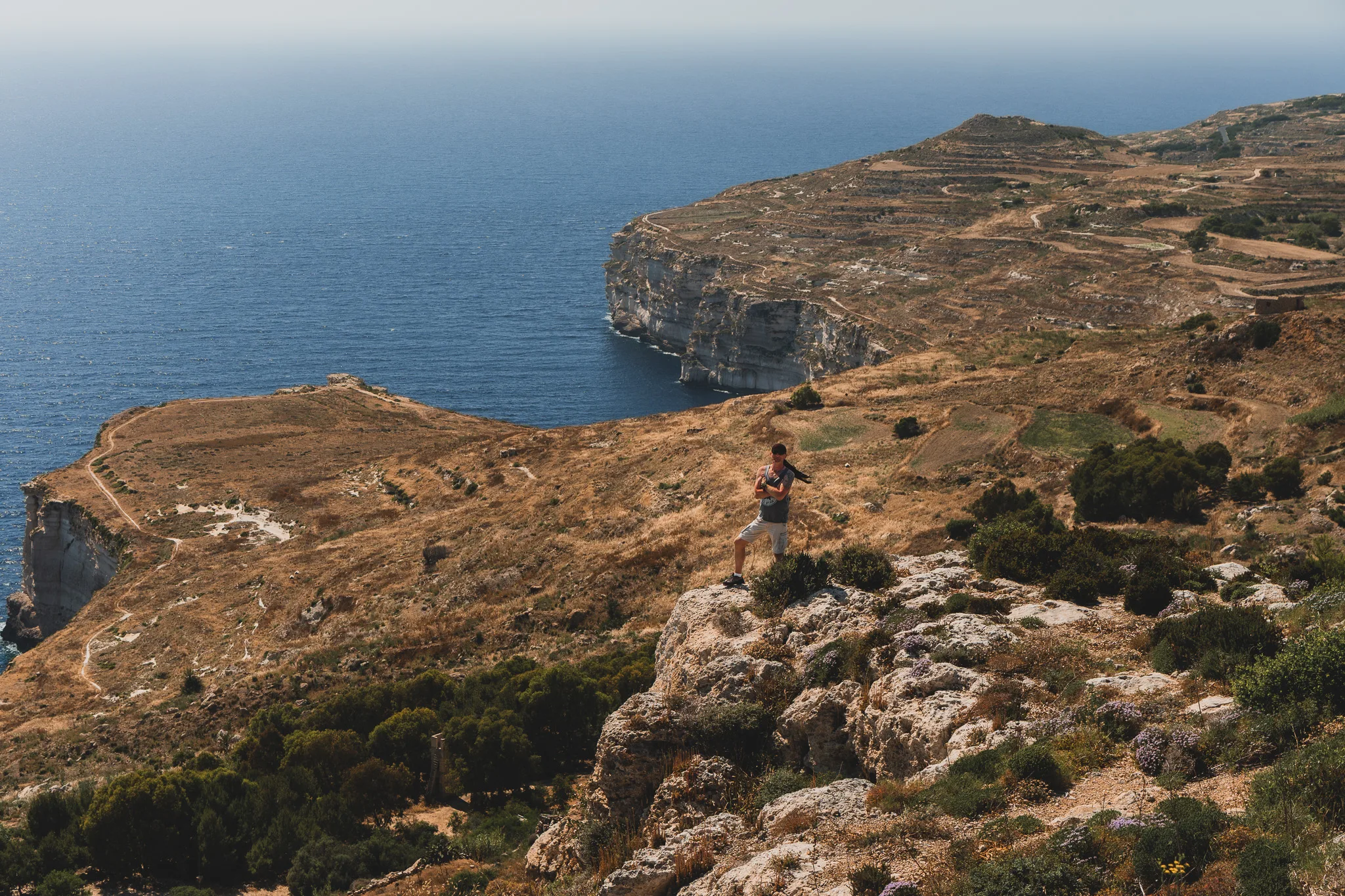 Panorama klifów Ras id-Dawwara na Malcie – turysta stojący na skale z widokiem na wybrzeże i Morze Śródziemne