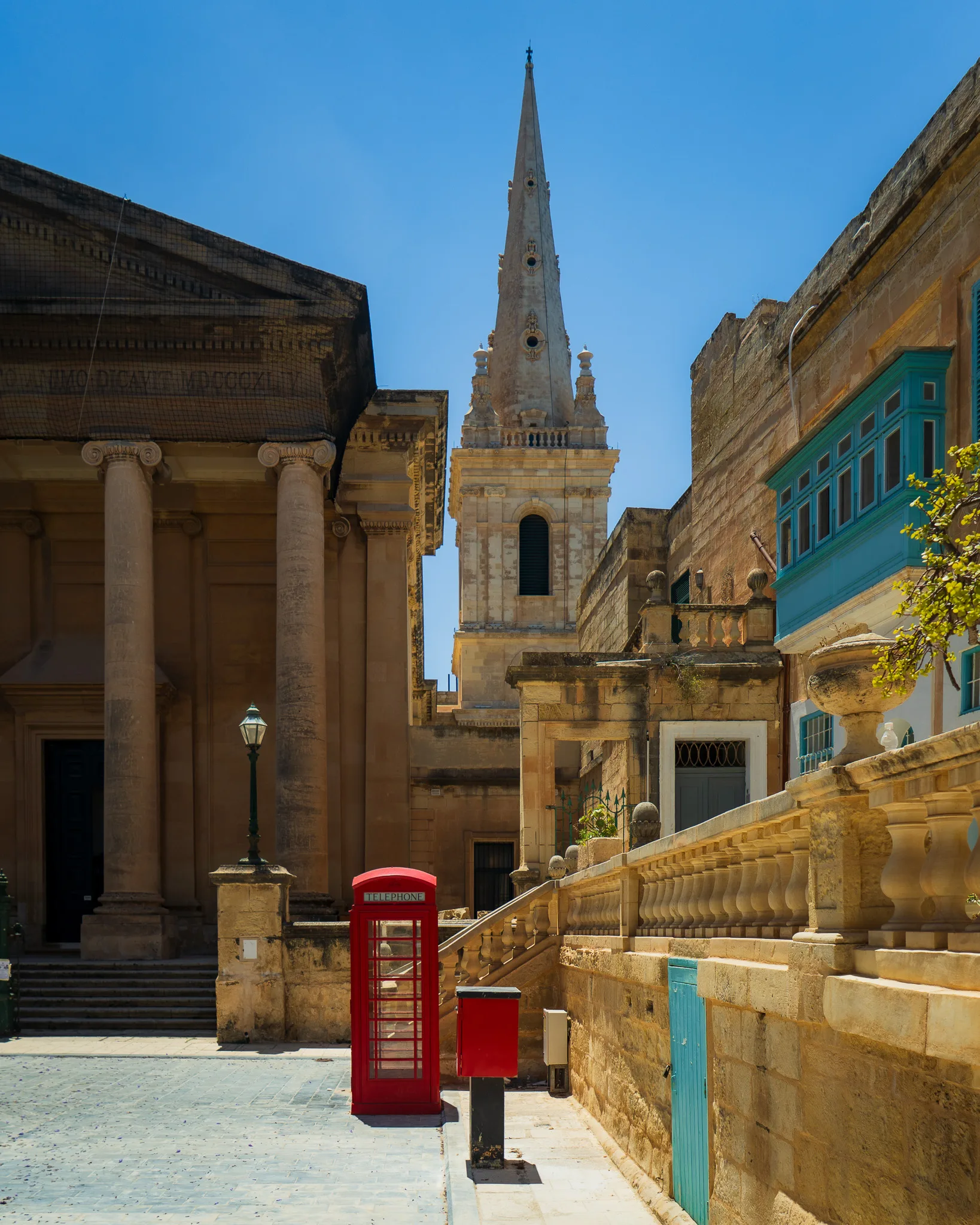 Czerwona budka telefoniczna na tle anglikańskiej katedry św. Pawła i klasycznej architektury Valletty – Malta