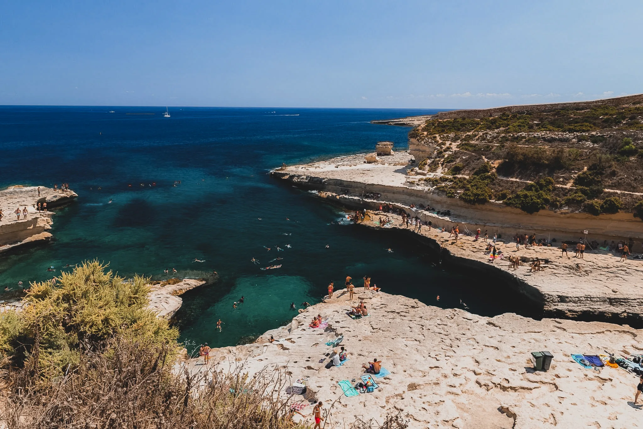 St. Peter’s Pool z lotu ptaka – naturalna zatoczka z lazurową wodą i otaczającymi ją tarasowymi polami, Malta