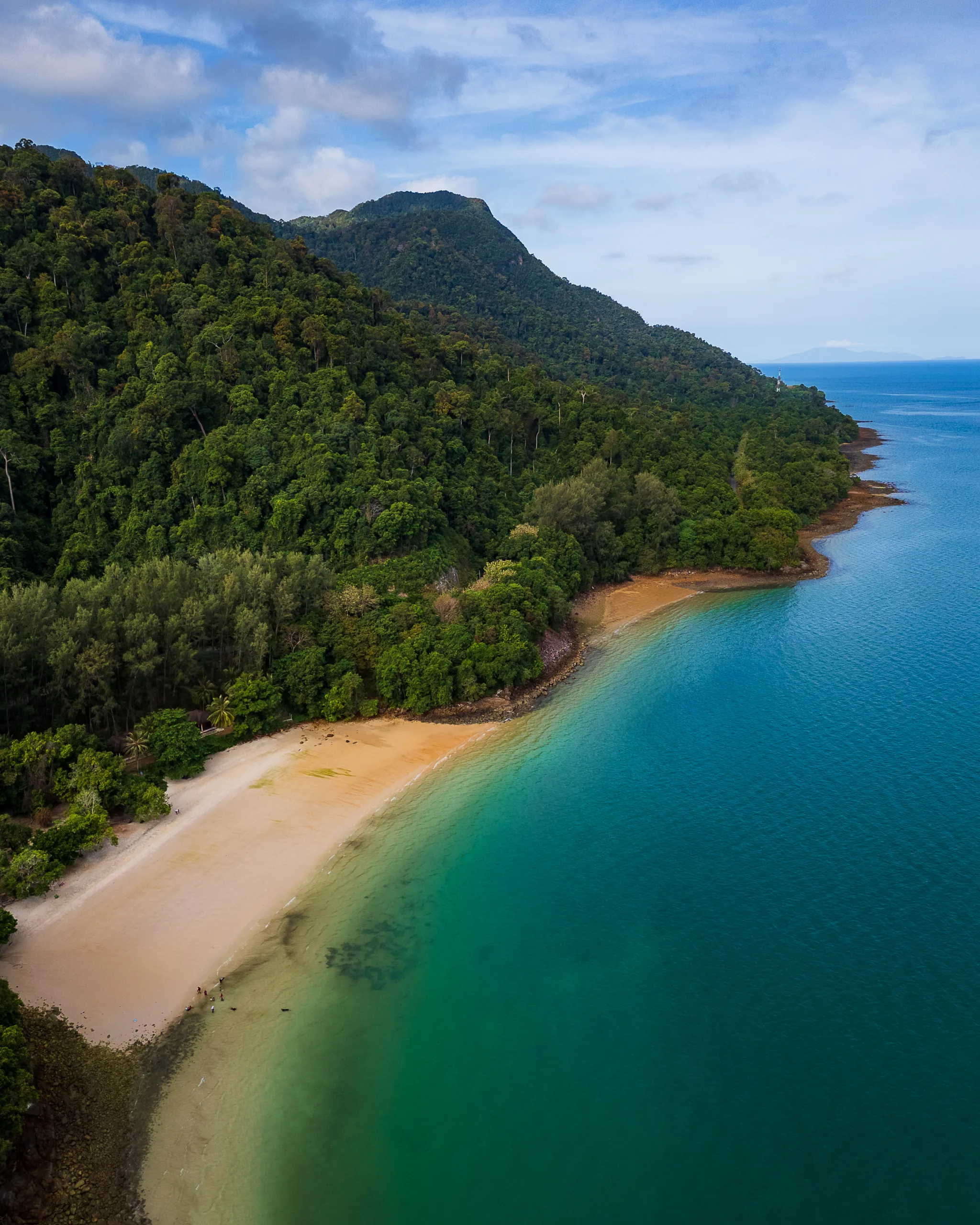 Dzika, pusta plaża otoczona tropikalną dżunglą i turkusową wodą u wybrzeży wyspy Langkawi w Malezji – widok z lotu ptaka