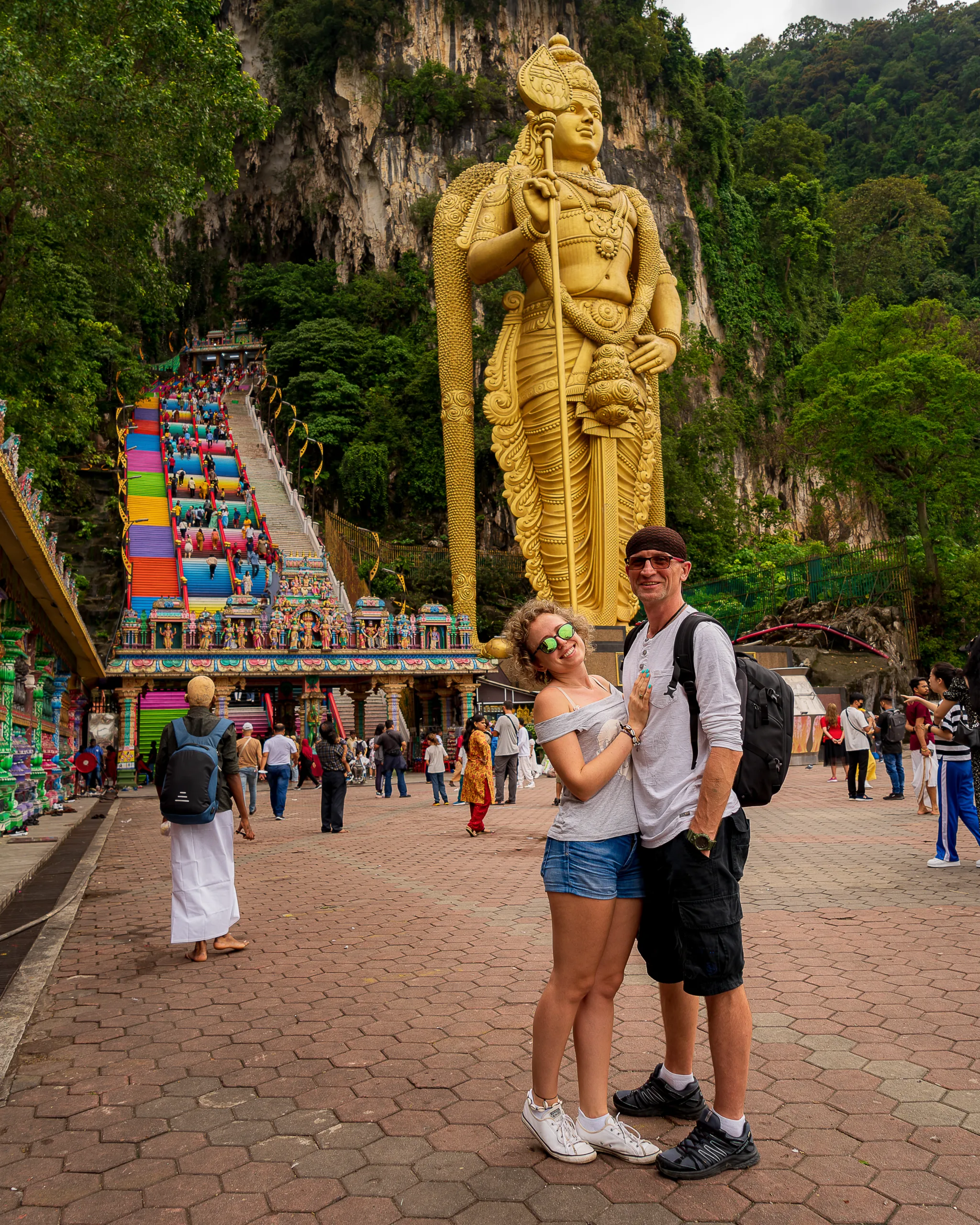 Turyści pozują przed złotym posągiem Murugana i kolorowymi schodami prowadzącymi do jaskiń Batu Caves w Malezji - co zobaczyć w malezji