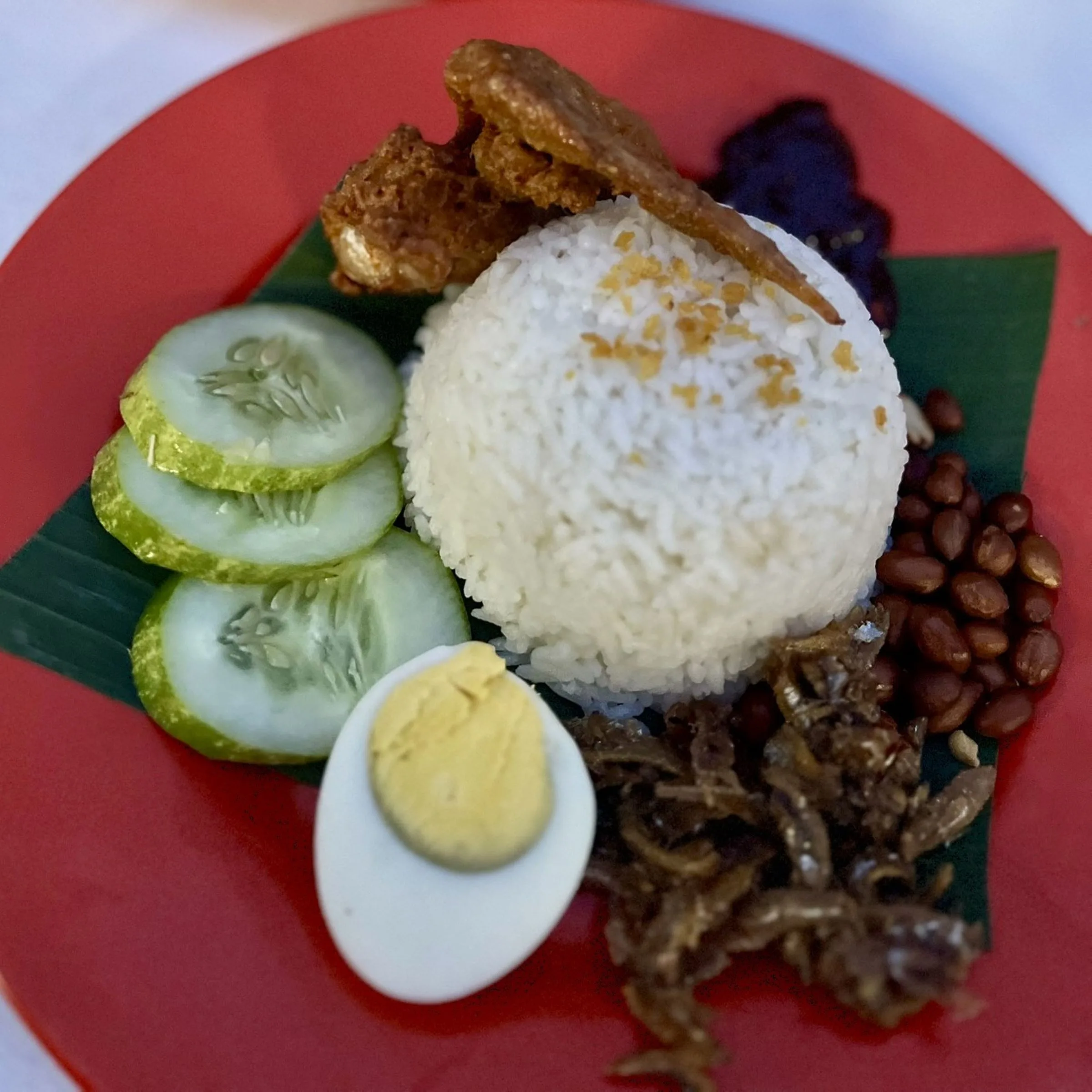 Tradycyjne malezyjskie Nasi Lemak – ryż gotowany w mleku kokosowym podany z jajkiem na twardo, ogórkiem, smażonymi anchois, orzeszkami ziemnymi, sambalem i kawałkiem kurczaka