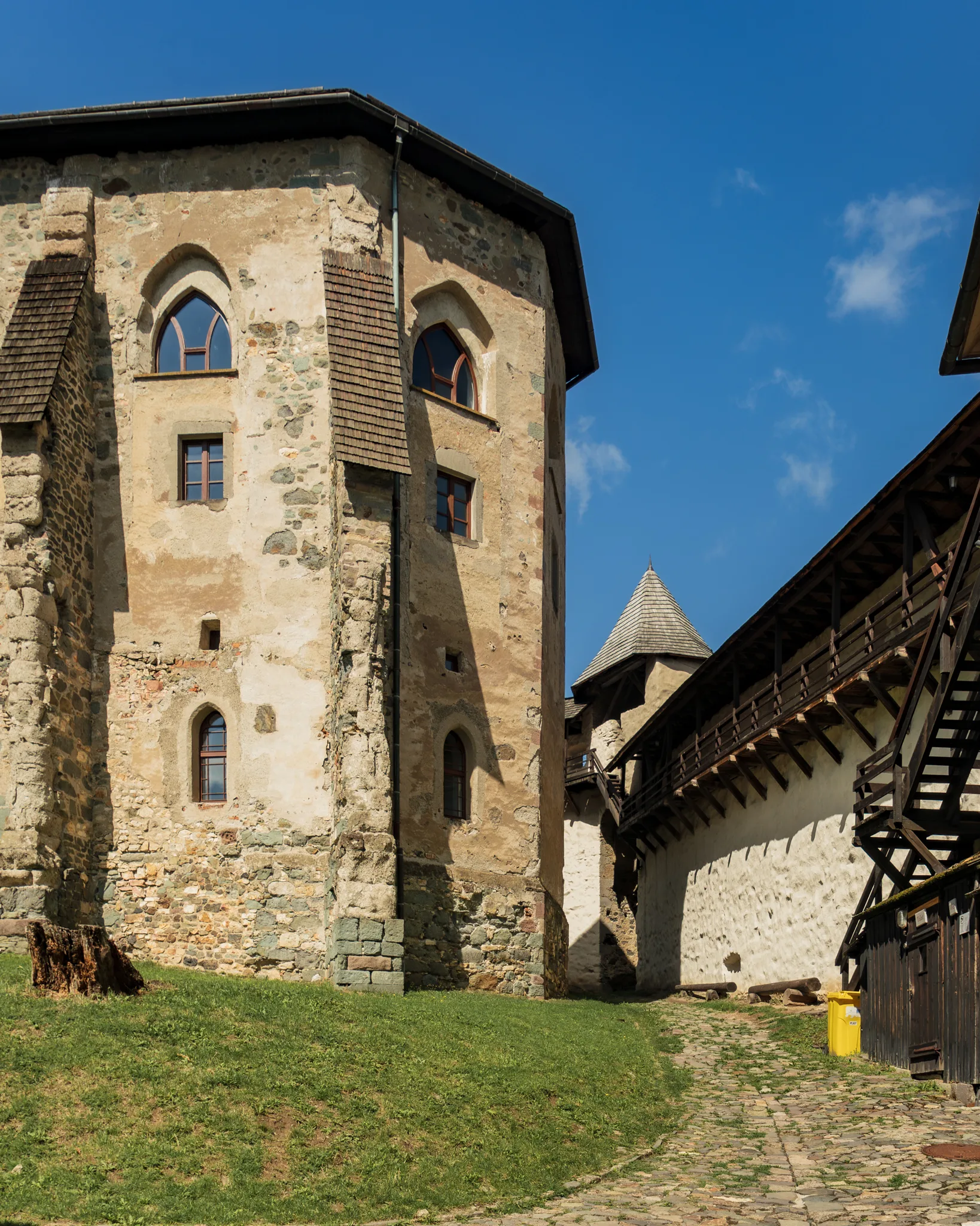 Fragment murów i kamiennej baszty Starego Zamku w Bańskiej Szczawnicy z widoczną ścieżką prowadzącą przez dziedziniec.