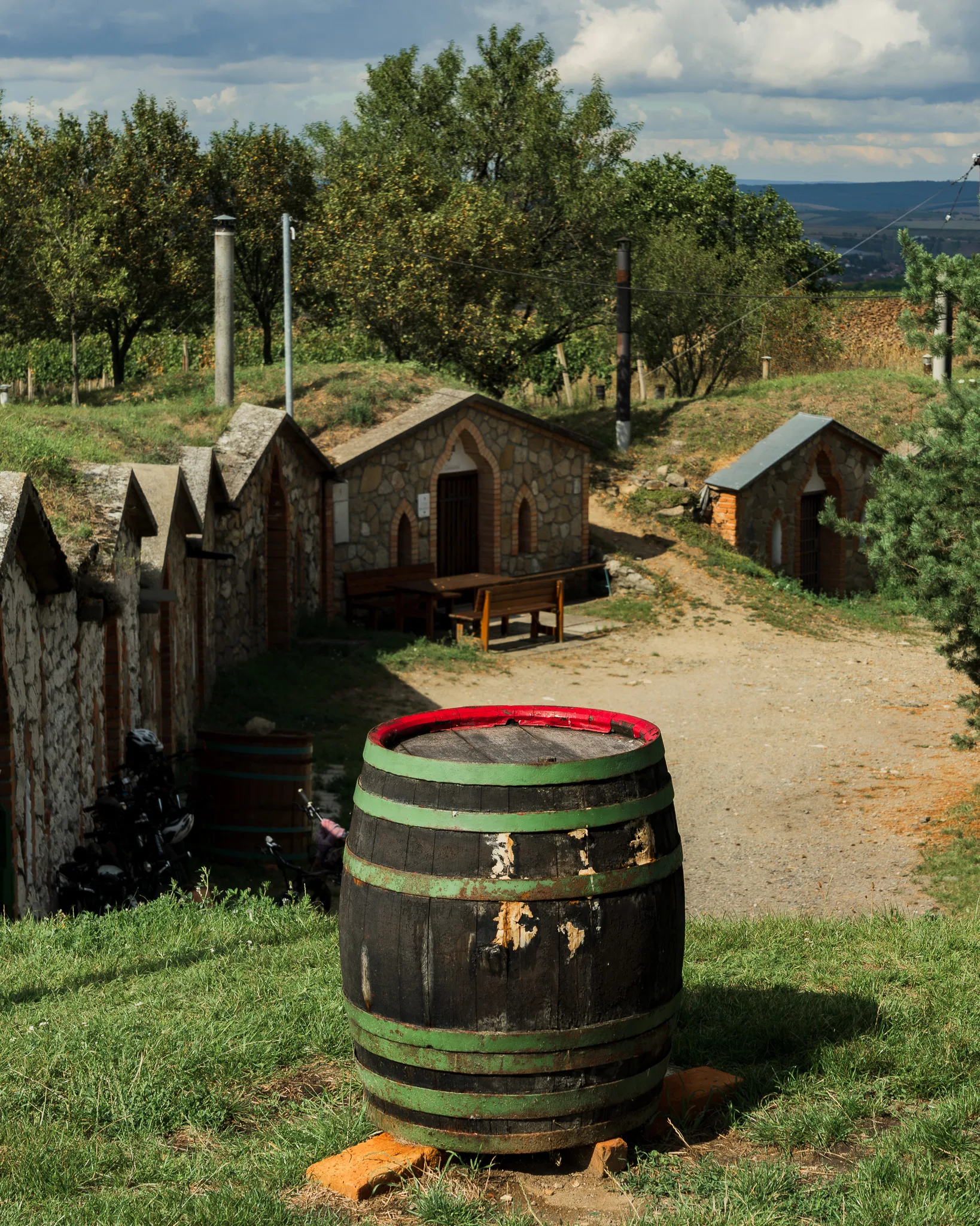 Tradycyjne piwniczki winne w Morawach Południowych z charakterystycznymi kamiennymi fasadami oraz drewniana beczka na pierwszym planie.
