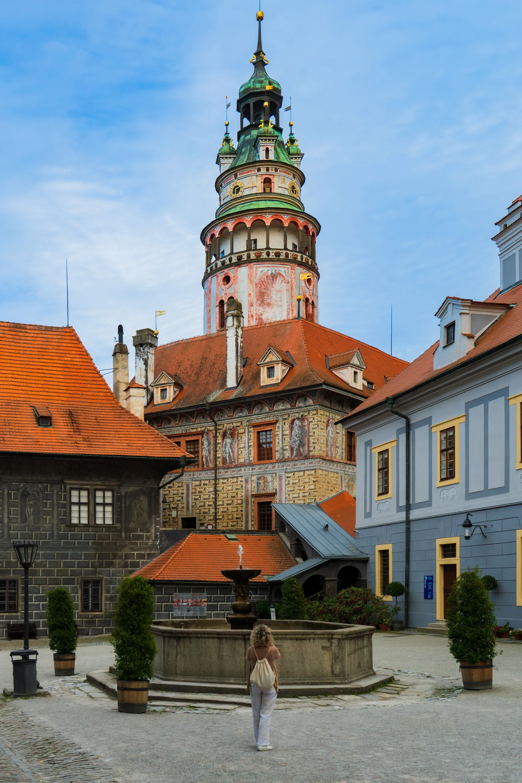 Dziedziniec zamku w Czeskim Krumlovie z kolorową wieżą i zdobionymi murami.