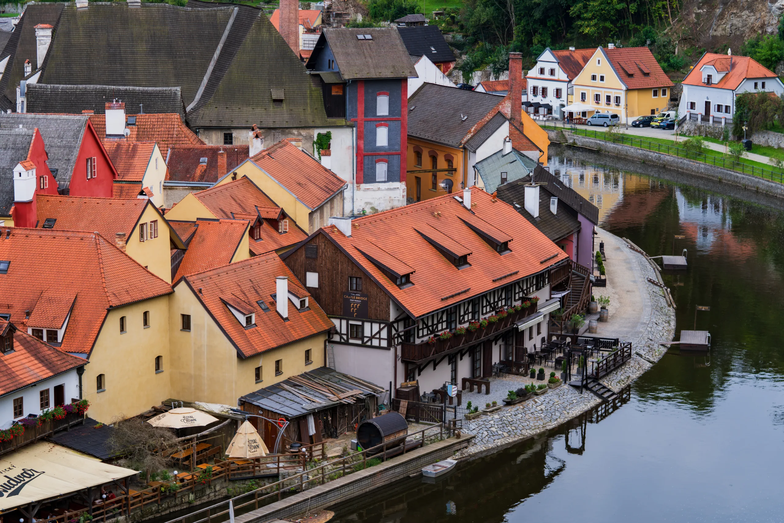 Kolorowe kamienice Českého Krumlova z czerwonymi dachami, nad brzegiem rzeky Wełtawy.