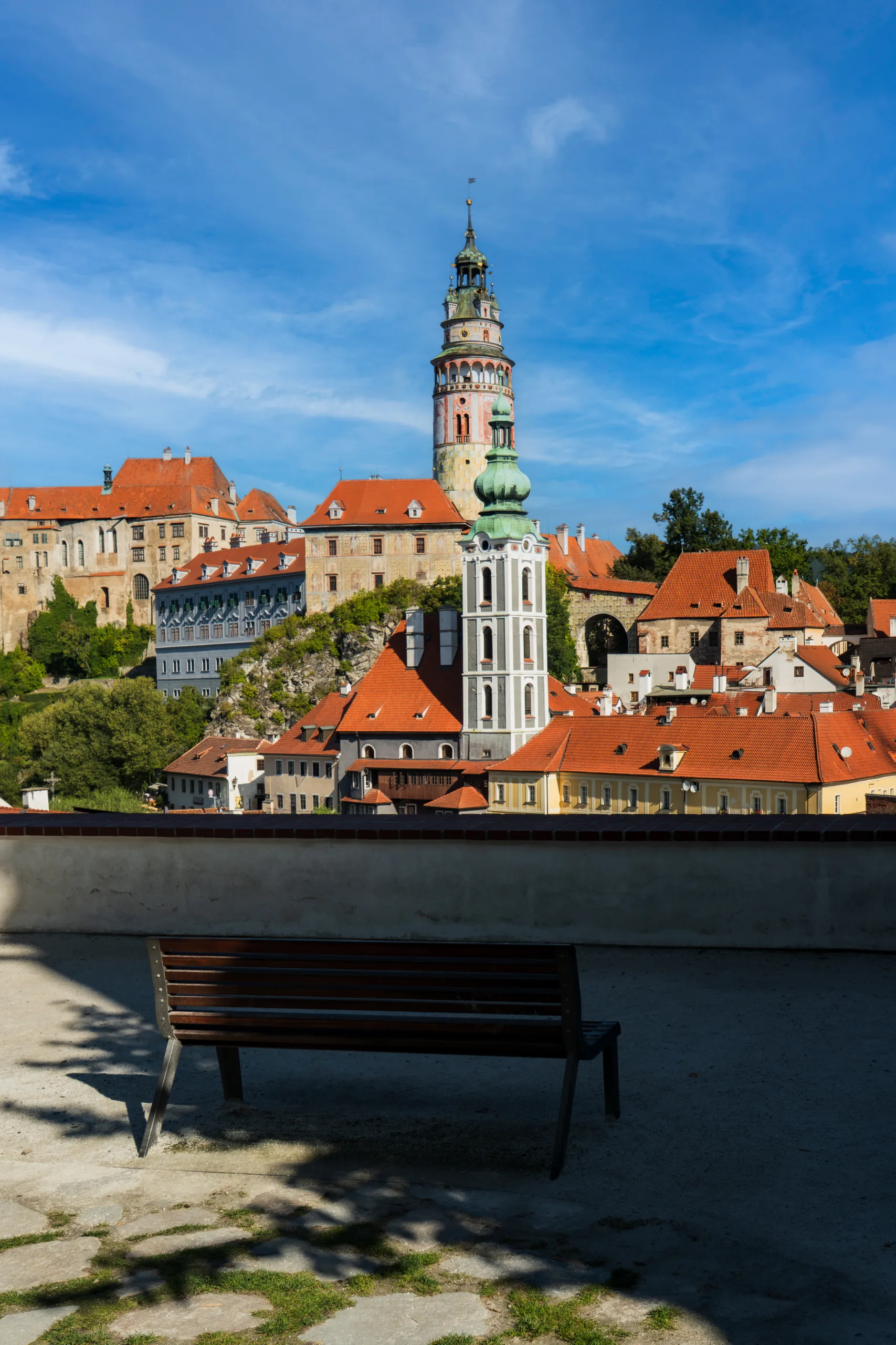 Panorama miasta Český Krumlov w Czechach z widokiem na zamek i kolorową wieżę zamkową oraz czerwone dachy kamienic.