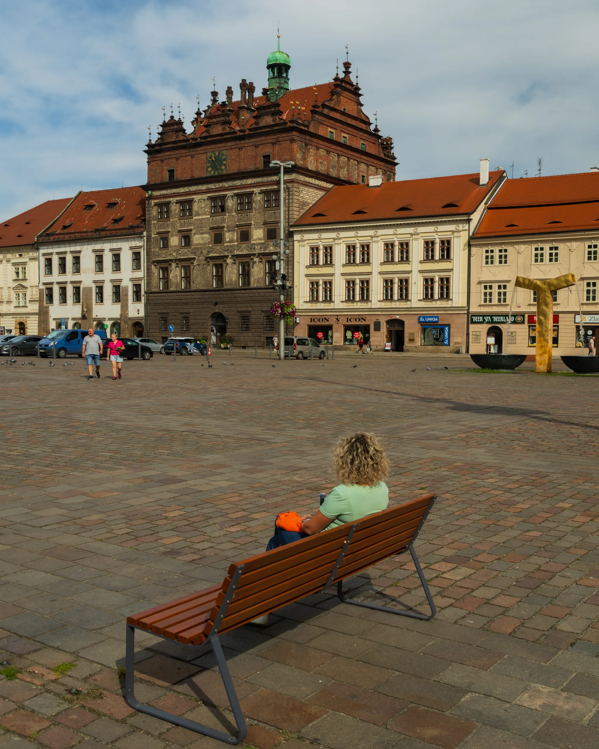 Renesansowy ratusz w Pilznie z ozdobną fasadą i wieżyczką zegarową, widok z rynku z ławką na pierwszym planie - Czechy.