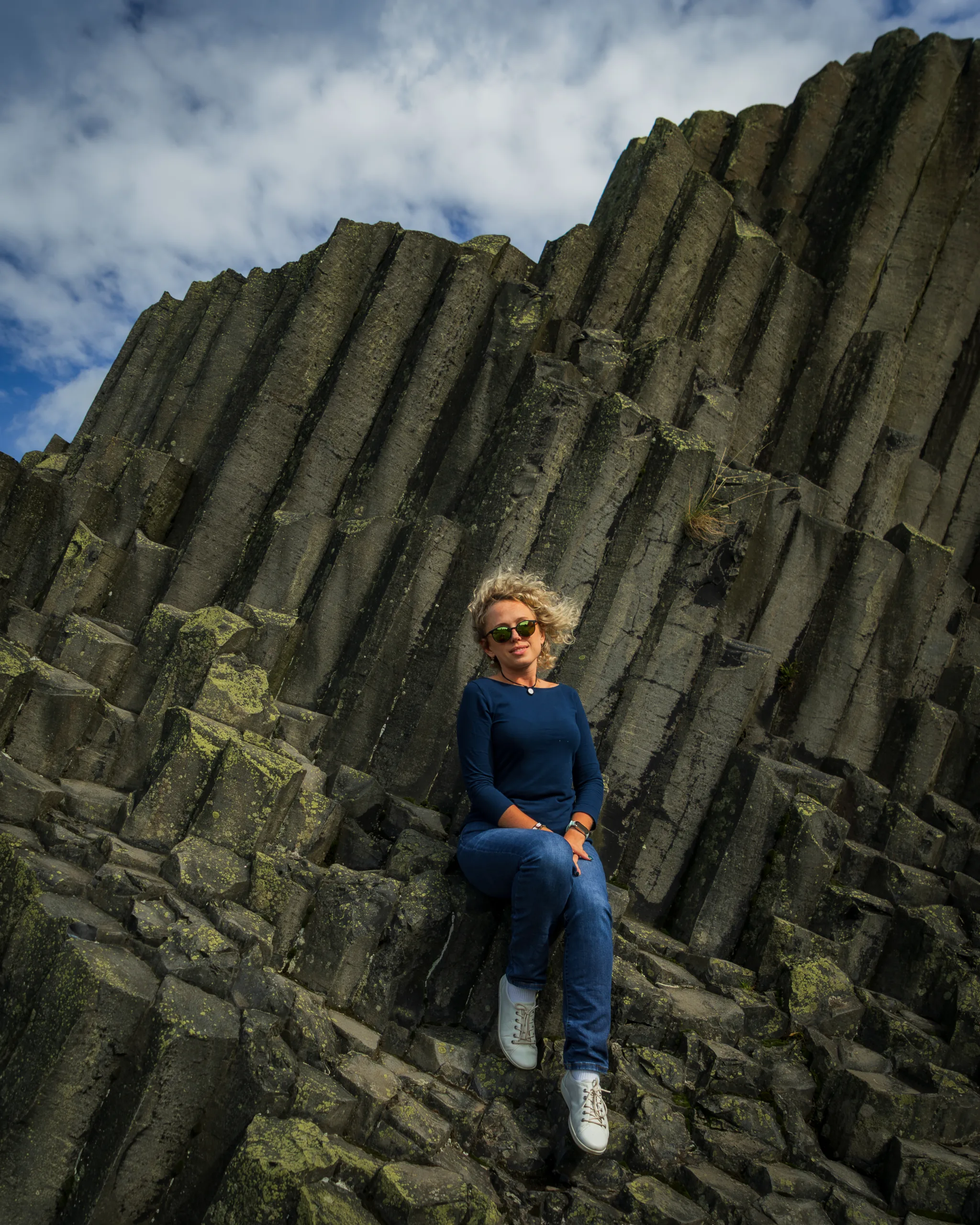 Kobieta siedząca na monumentalnych bazaltowych słupach skalnych w Czeskim Raju - Czeska Szwajcaria.