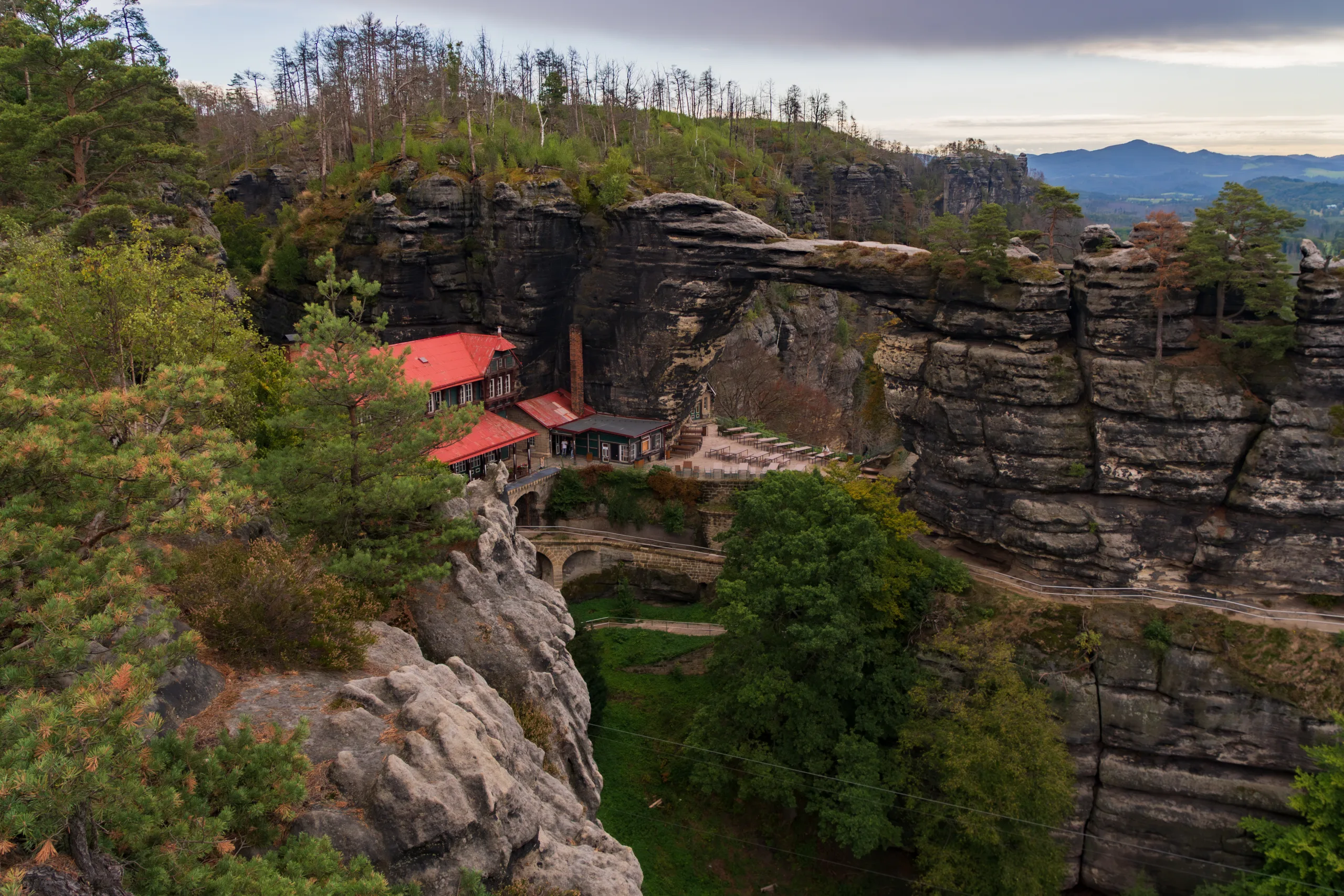 Pravčická Brána w Czeskiej Szwajcarii – największy skalny most w Europie, z charakterystycznym czerwonym dachem schroniska Sokolí hnízdo u podnóża formacji.