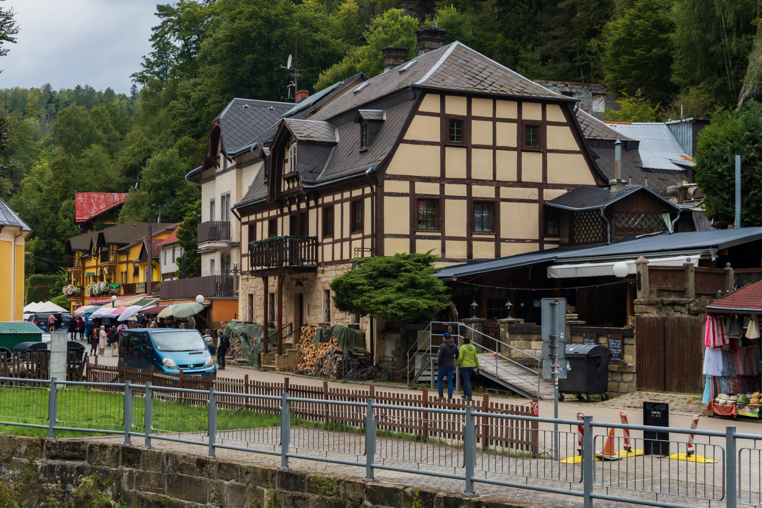 Ulica w Hřensku w Czeskiej Szwajcarii z tradycyjnymi domami o muru pruskim, kolorowymi budynkami i straganami pełnymi turystów.