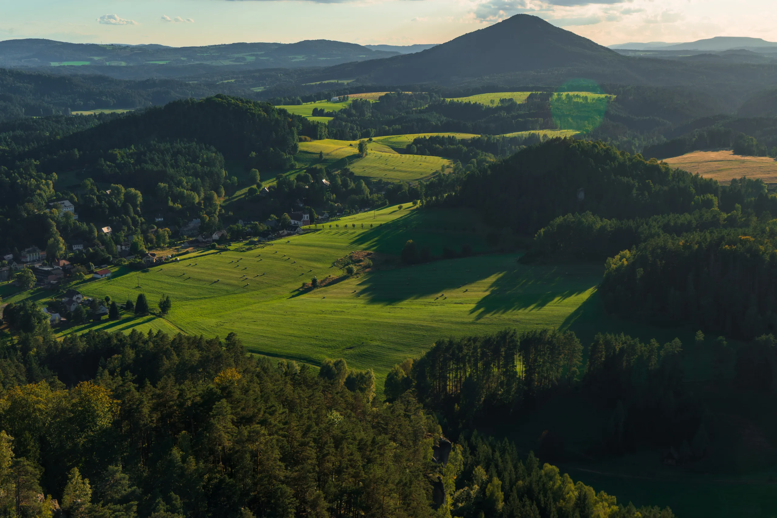 Panorama zielonych łąk, lasów i pagórków w Czeskiej Szwajcarii oglądana z punktu widokowego.