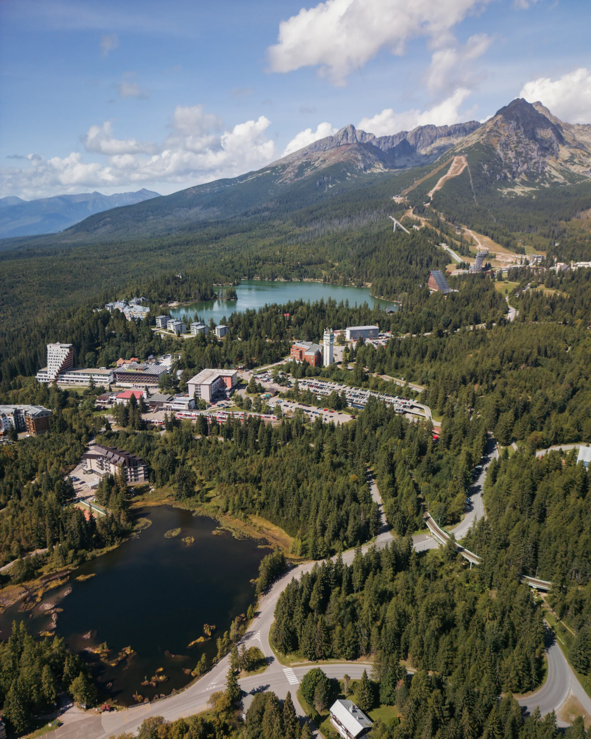 Štrbskie Jezioro w Tatrach Wysokich z lotu ptaka, widok na jeziora, hotele i stoki narciarskie na tle gór.