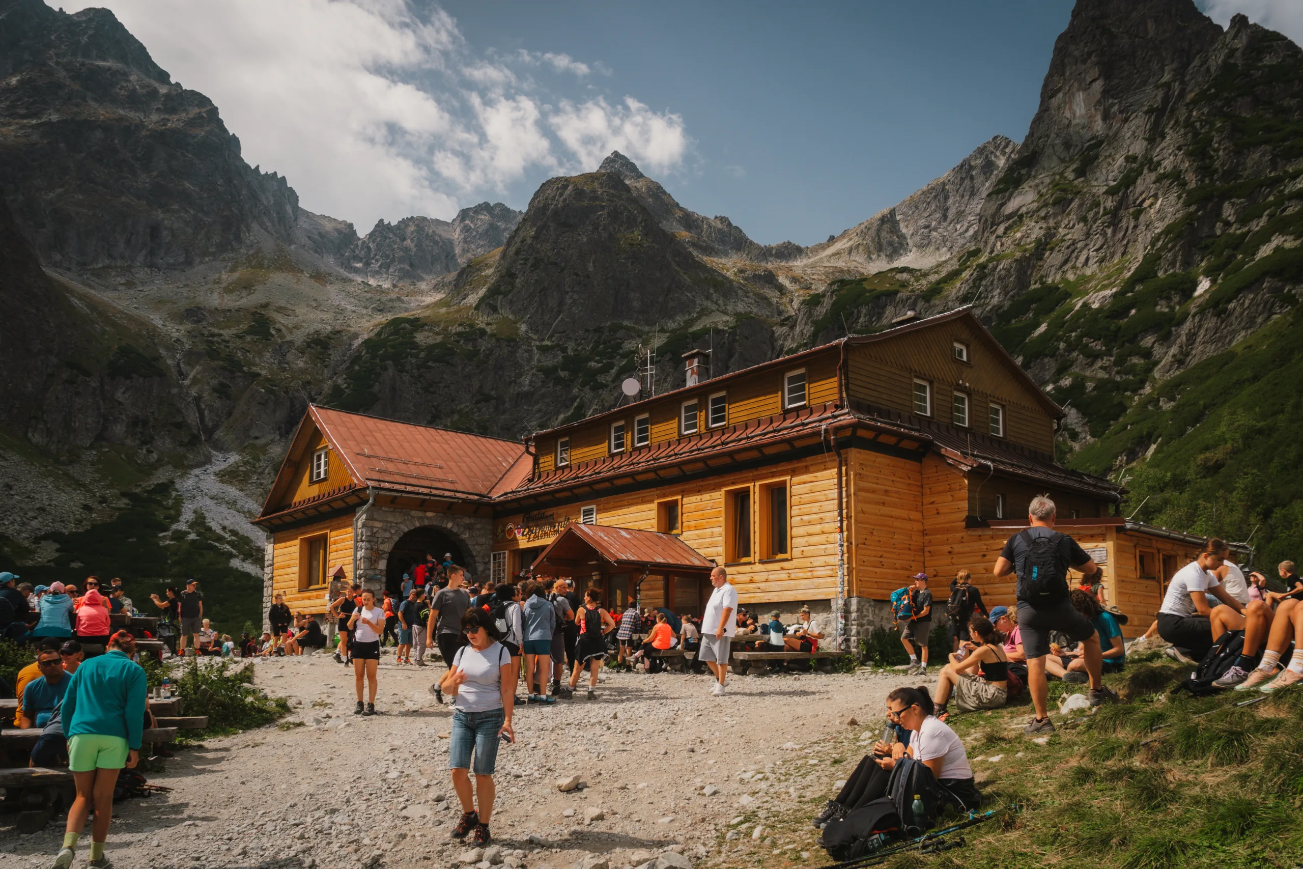Schronisko górskie nad Zelenym plesem w Tatrach Wysokich, otoczone turystami i majestatycznymi szczytami.