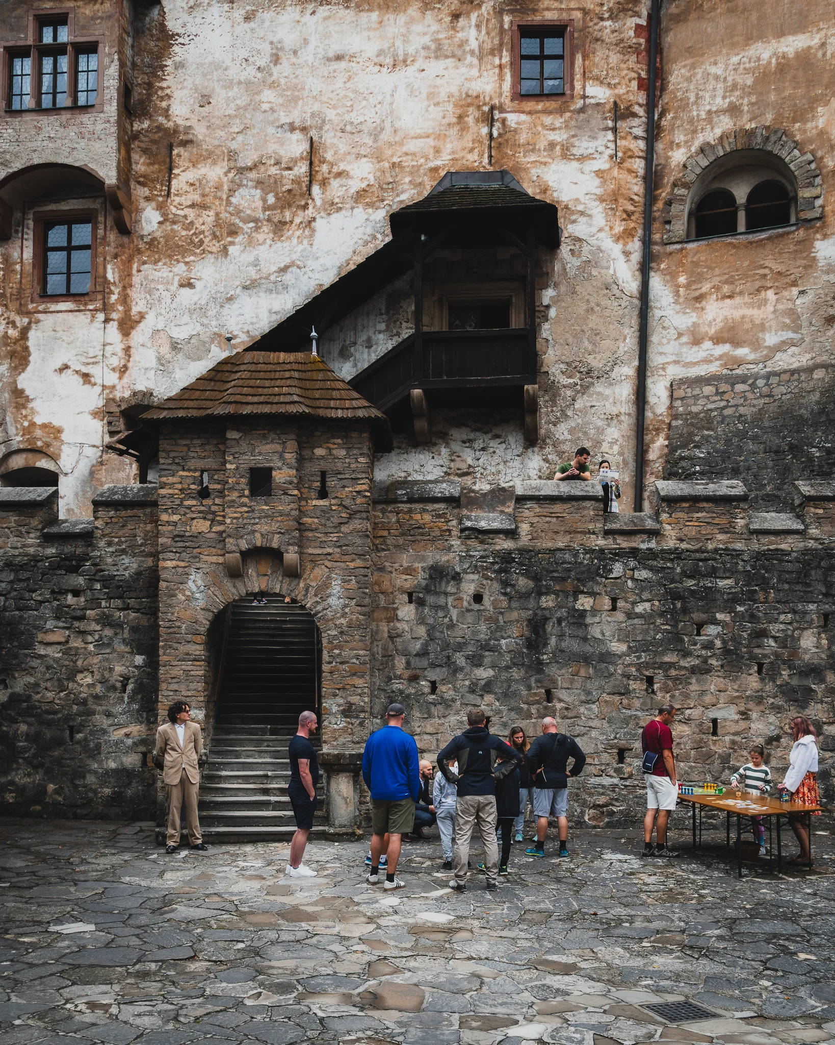 Dziedziniec Zamku Orawskiego na Słowacji z kamiennymi murami, schodami prowadzącymi na wyższe kondygnacje i turystami zwiedzającymi wnętrze.
