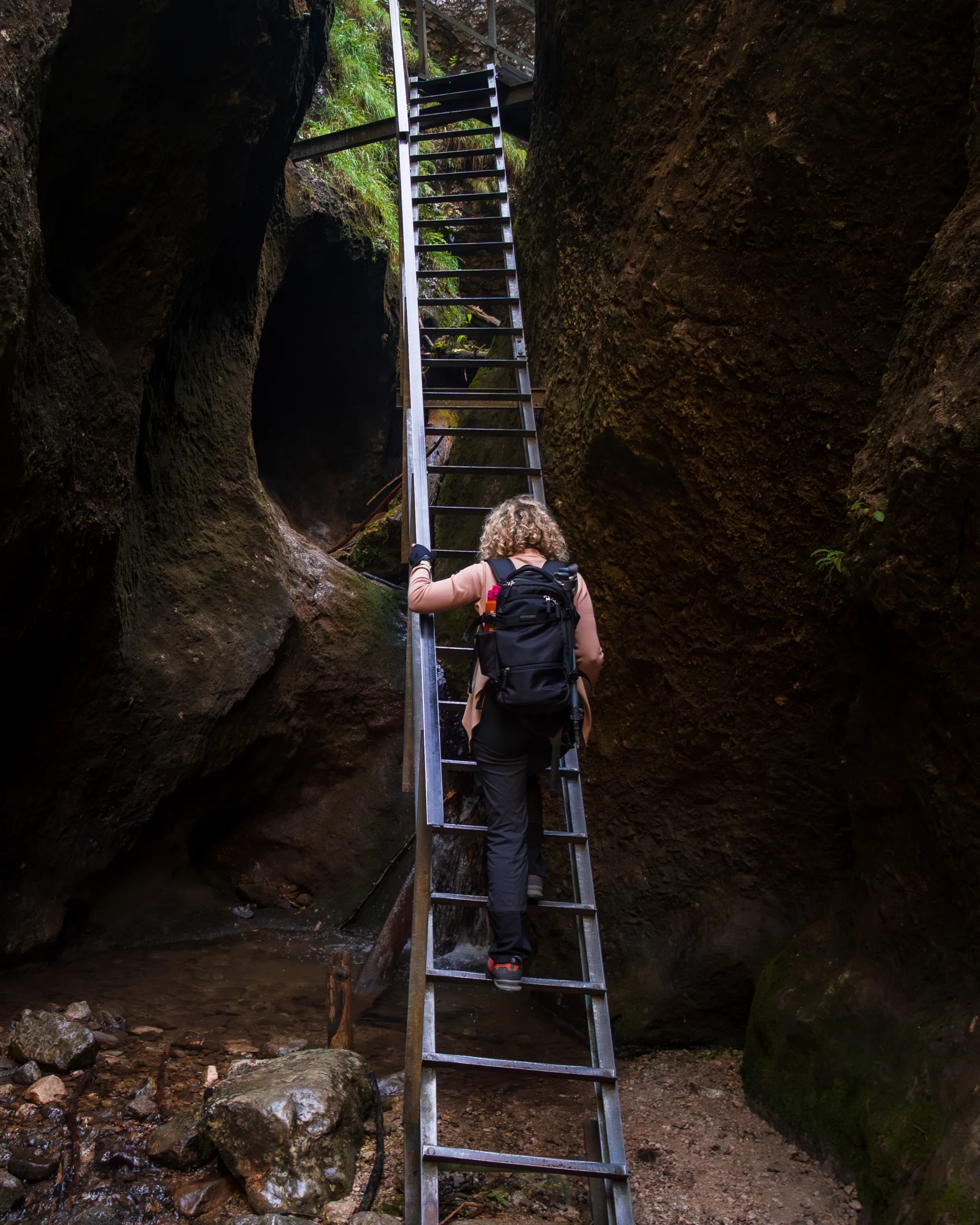 Turystka wspinająca się po metalowej drabince w wąwozie Jánošíkowe Diery w Małej Fatrze.