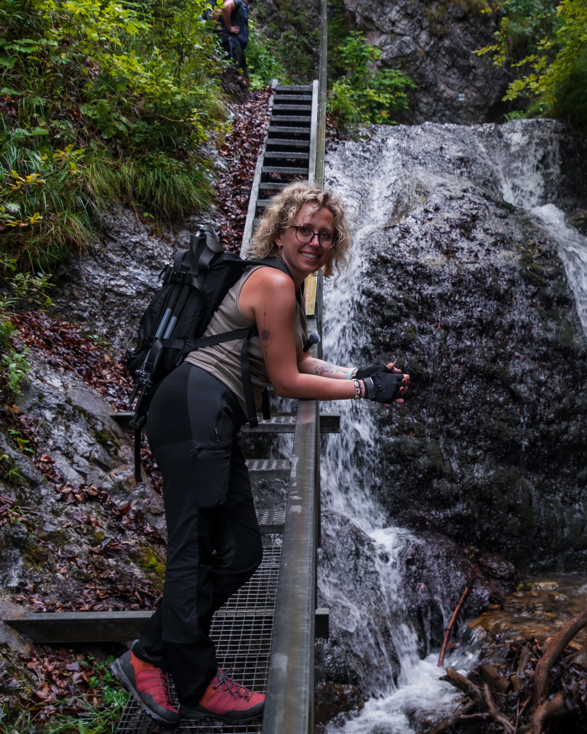 Turystka na metalowej kładce przy wodospadzie w wąwozie podczas trekkingu w Małej Fatrze.