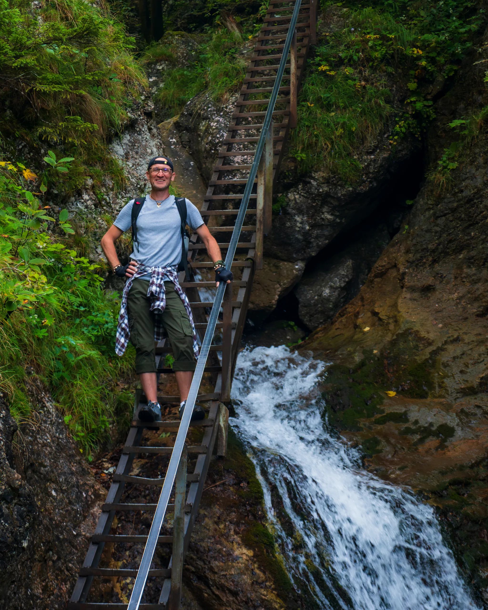 Turysta na metalowej drabince obok wodospadu podczas trekkingu w małej Fatrze.