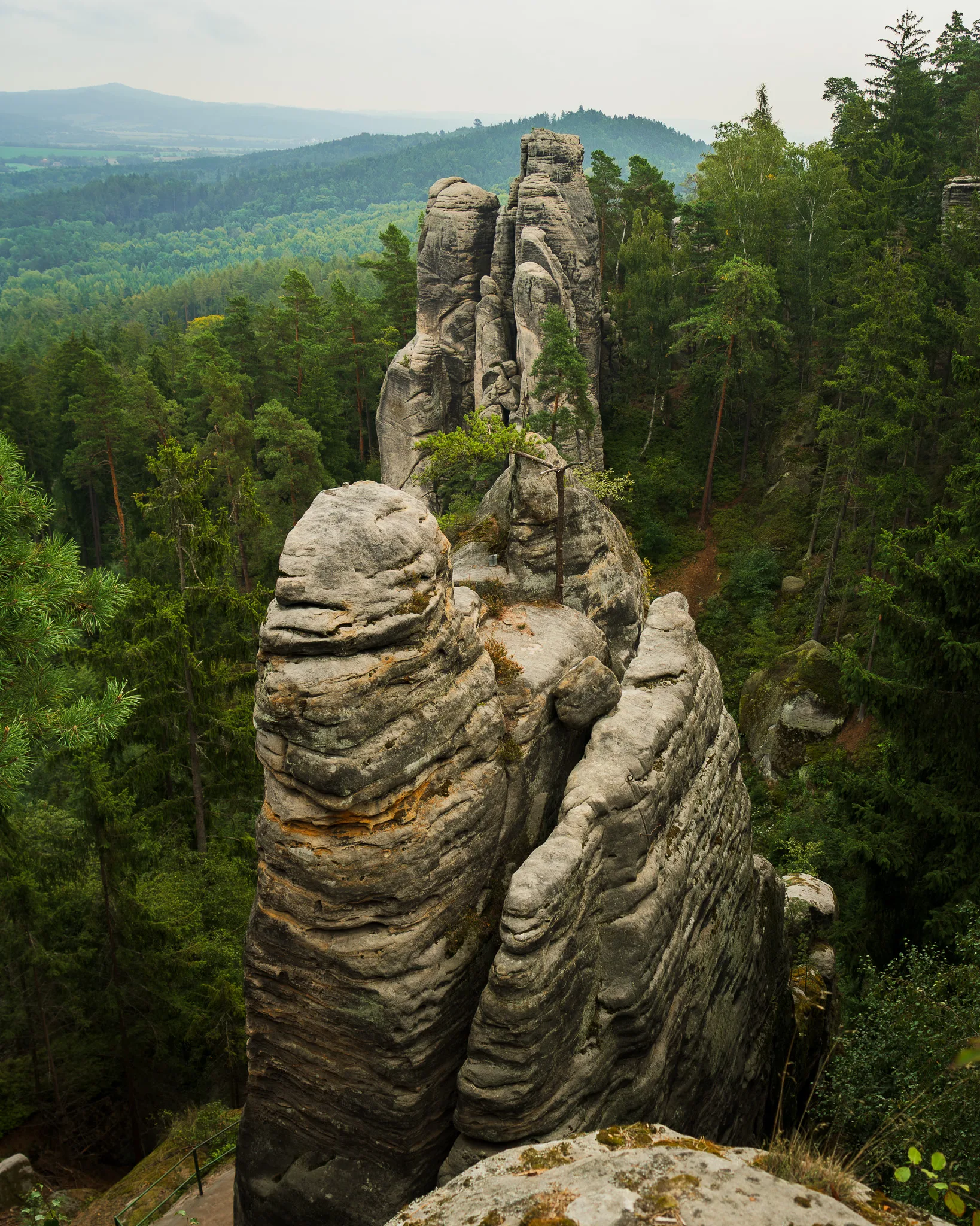 Malownicze formacje skalne w Czeskim Raju otoczone gęstym lasem i rozciągającym się widokiem na zielone wzgórza - Czeski Raj.