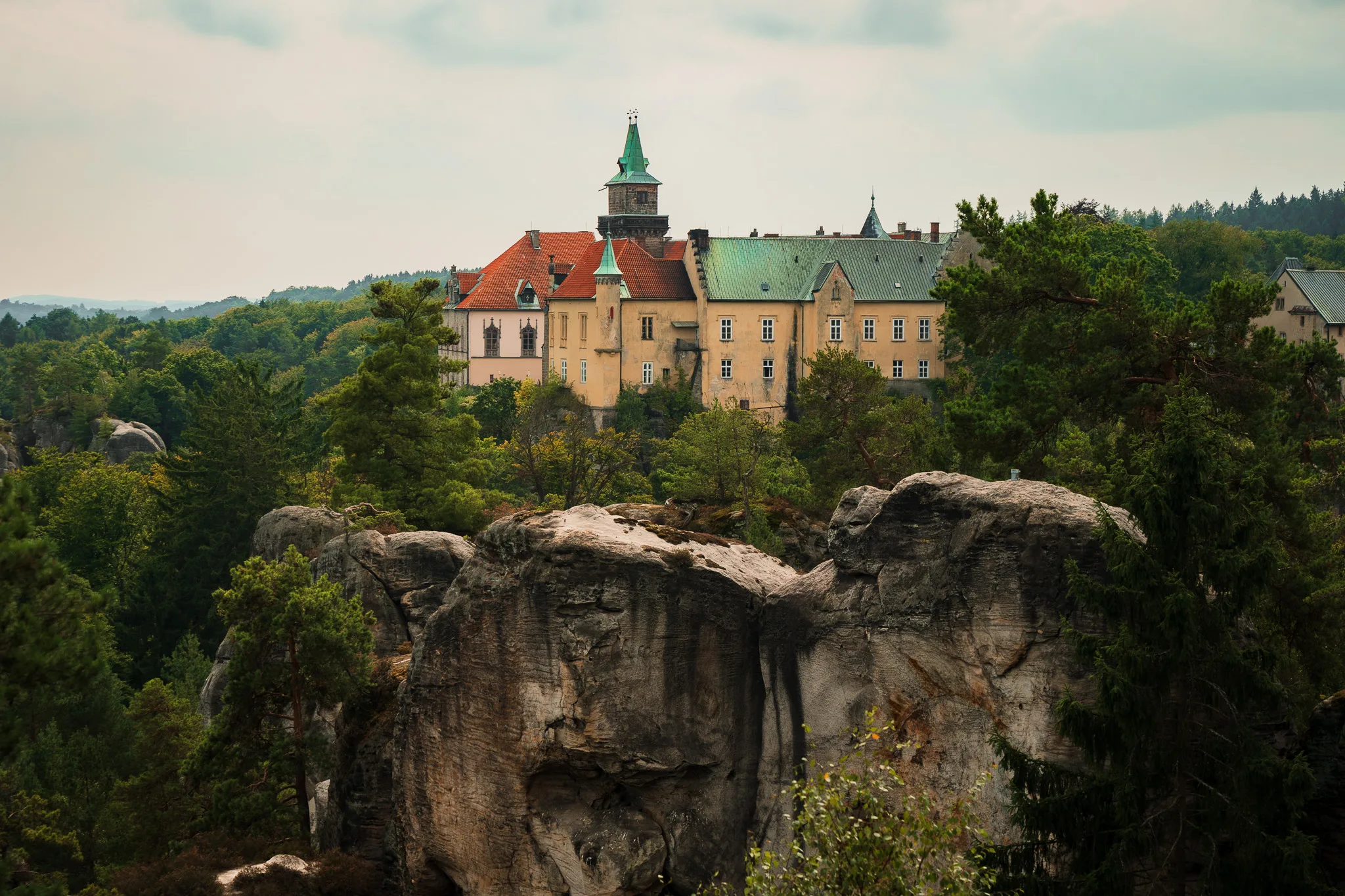 Zamek Hrubá Skála w Czeskim Raju położony malowniczo na skale, otoczony lasami i piaskowcowymi formacjami skalnymi.