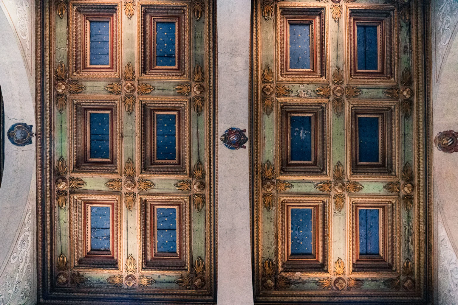 Zdobiony sufit z drewnianych kasetonów w złotych i niebieskich barwach z gwiazdami w rzymskim kościele.