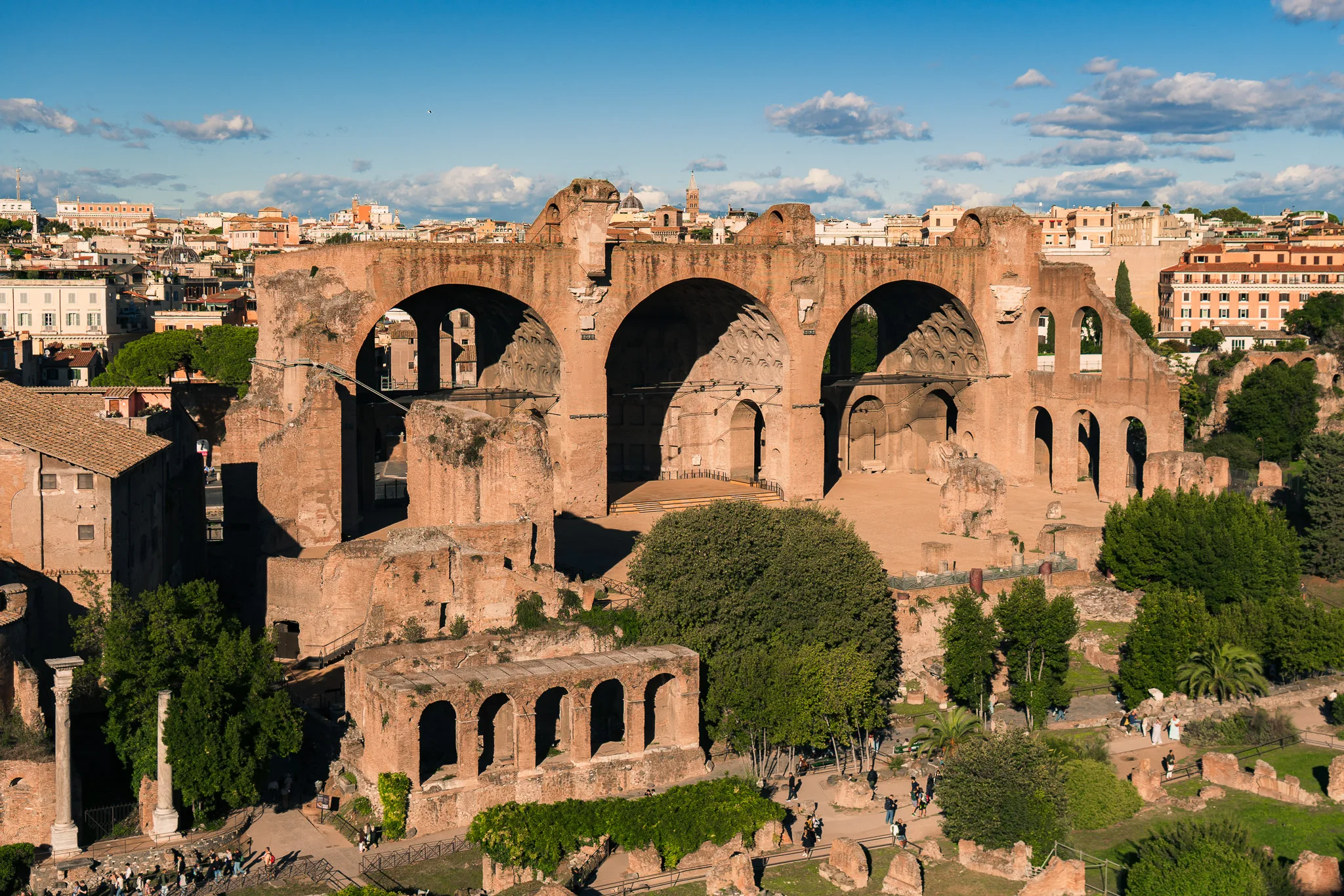 Bazylika Maksencjusza i Konstantyna na Forum Romanum w Rzymie, z widokiem na starożytne ruiny i miasto w tle.