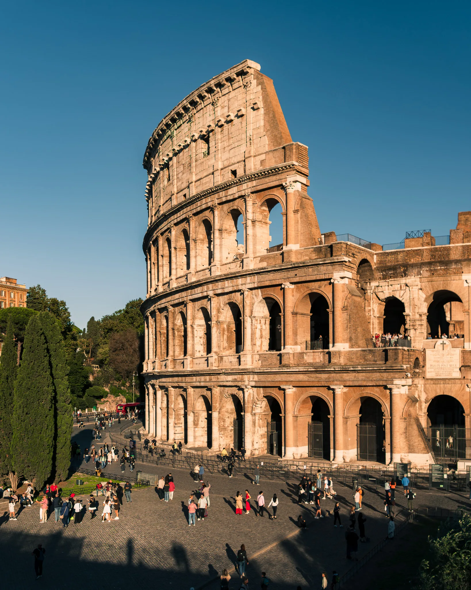 Koloseum w Rzymie o zachodzie słońca, z turystami spacerującymi wokół starożytnego amfiteatru - rzym włochy