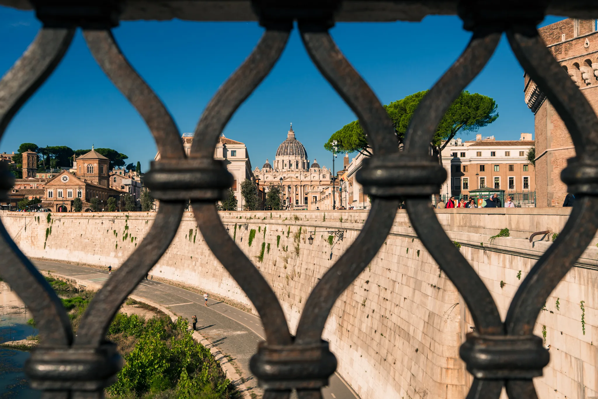 Bazylika Świętego Piotra w Watykanie widziana przez ozdobną kratę mostu nad Tybrem w Rzymie.