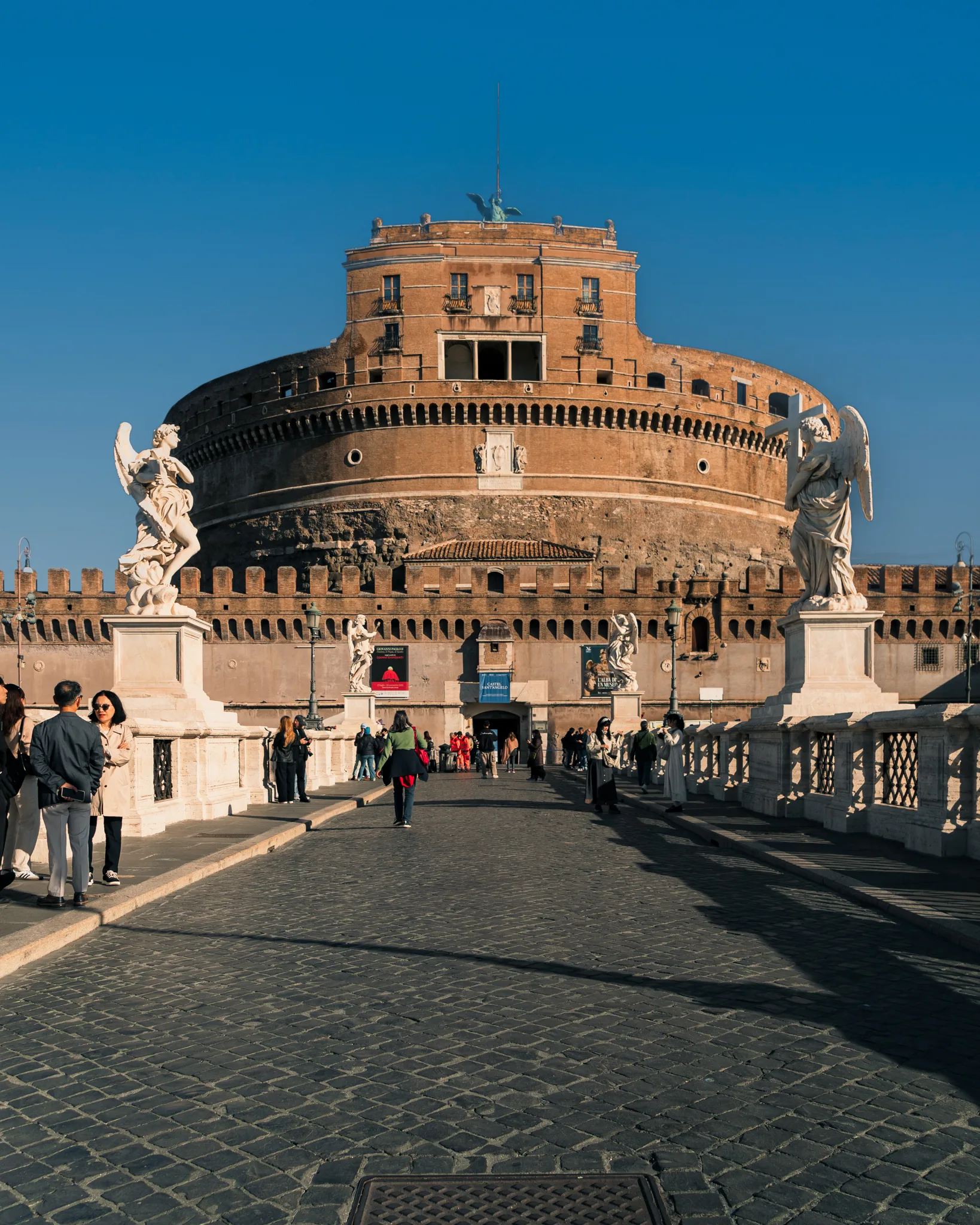 Zamek Świętego Anioła w Rzymie widziany z mostu Sant’Angelo z rzeźbami aniołów po obu stronach.