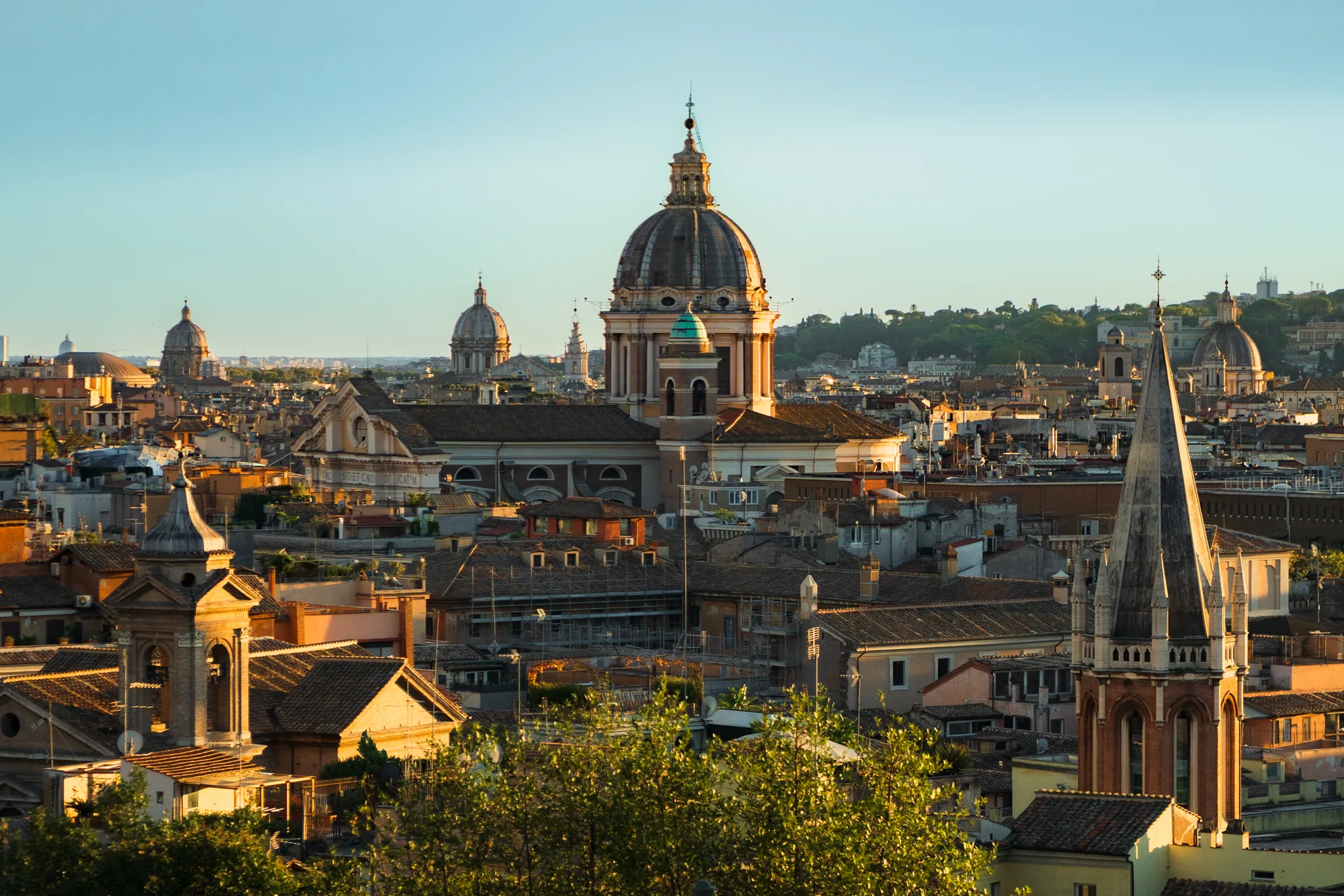 Panorama Rzymu o zachodzie słońca z widokiem na kopuły i dachy historycznego centrum miasta.